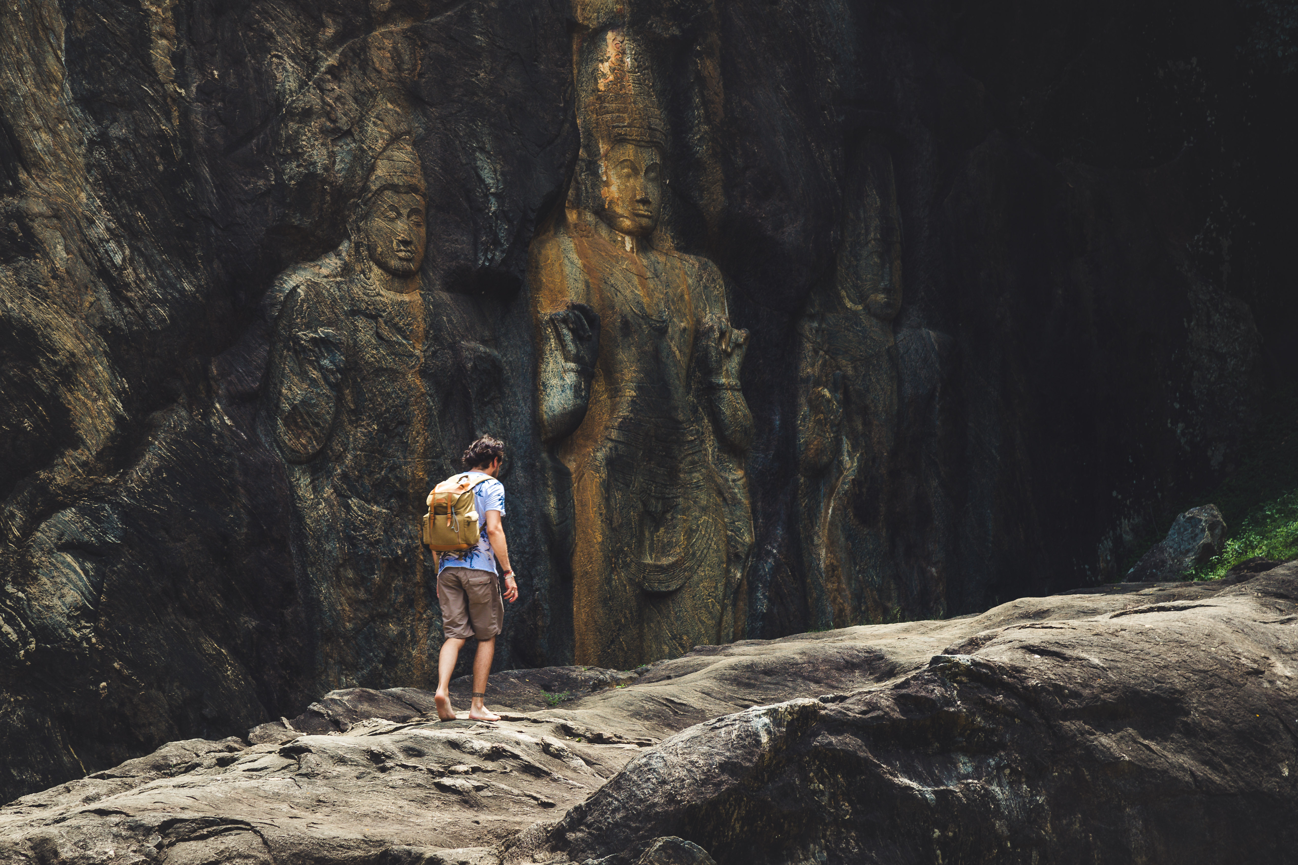 Backpacker udforsker de antikke buddhistiske klippefigurer ved Buduruvagala i Sri Lanka