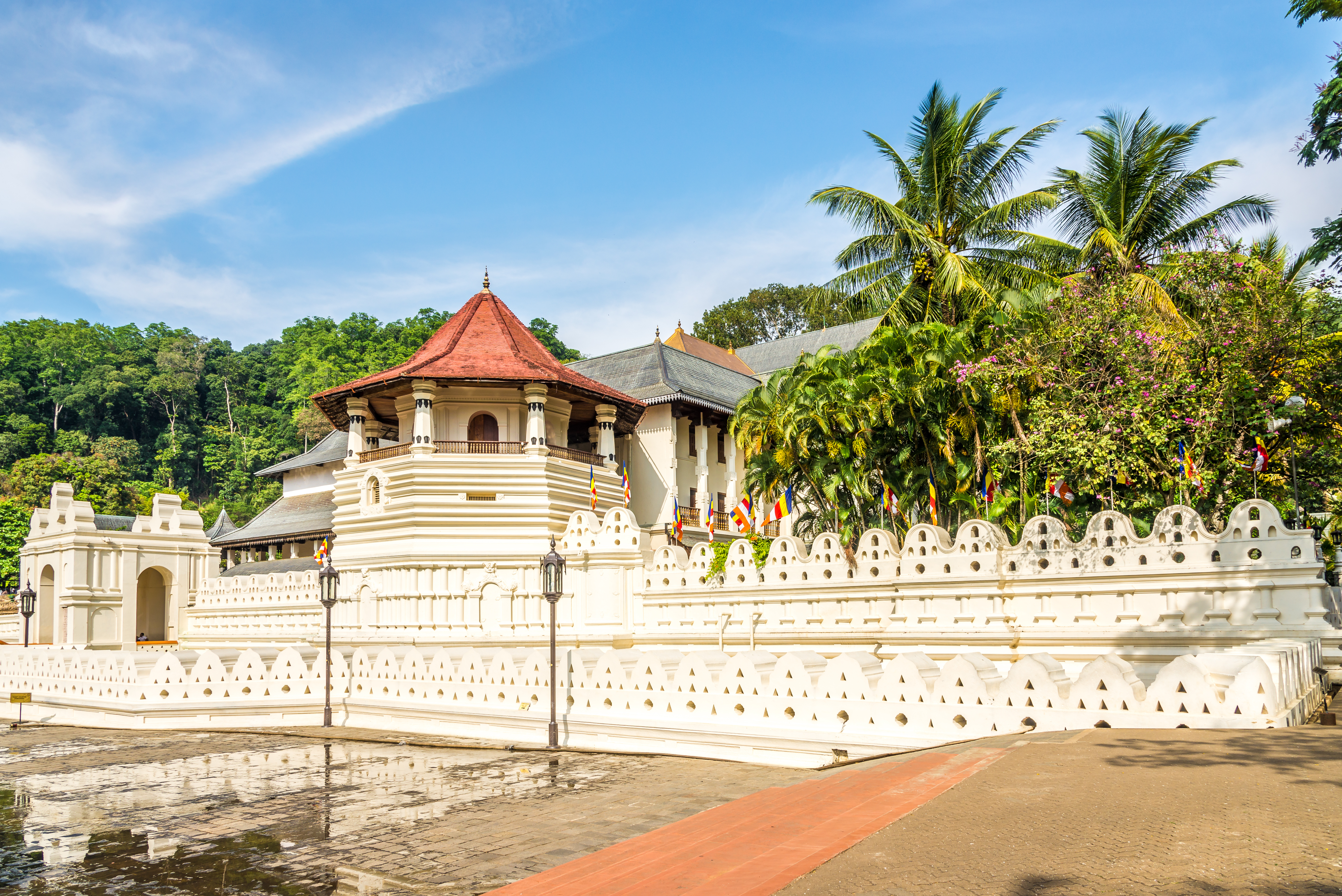 Det hellige tandtempel i Kandy, Sri Lanka, med smukke hvide mure, dekorativt ottekantettårn med rødt tag og farverige buddhistiske flag