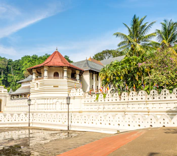 Det hellige tandtempel i Kandy, Sri Lanka, med smukke hvide mure, dekorativt ottekantettårn med rødt tag og farverige buddhistiske flag