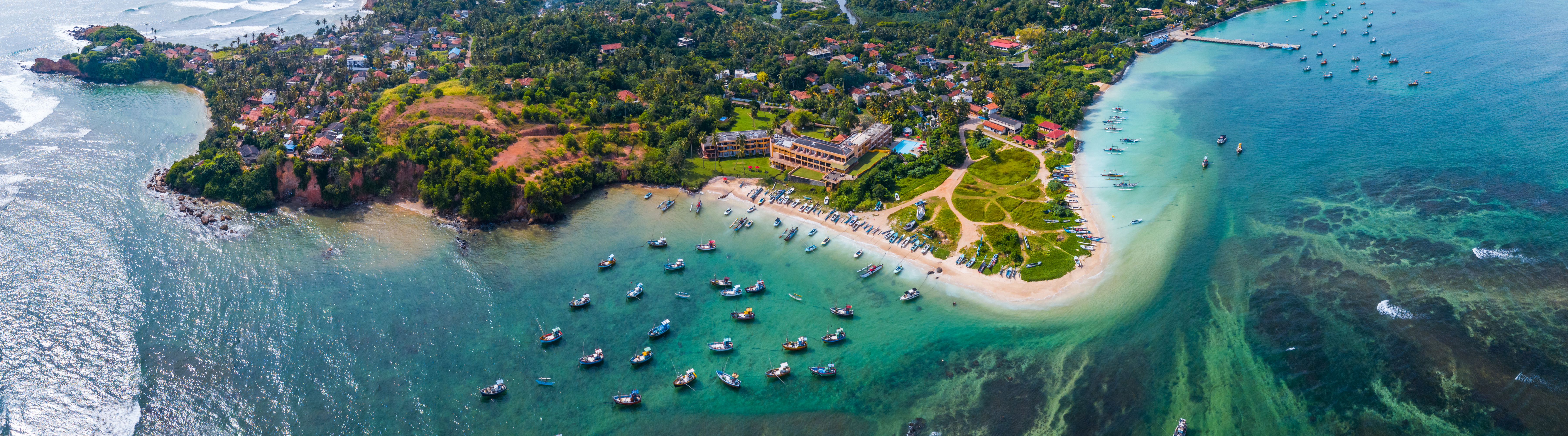 Luftpanorama over Weligama Bay i Sri Lanka med det karakteristiske turkise hav, koralrev og den frodige tropiske vegetation