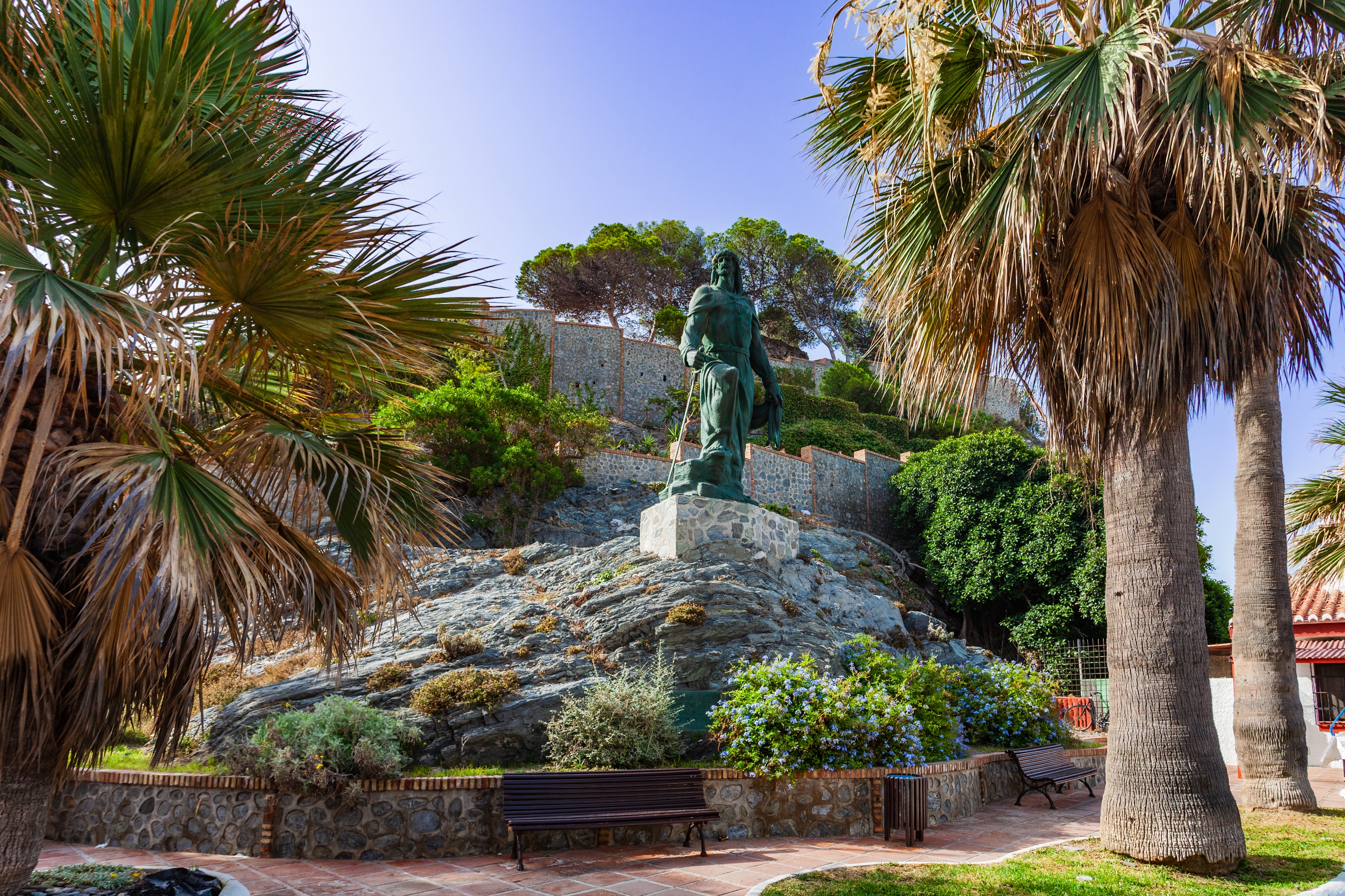 Grøn bronzestatue omgivet af palmer og mediterrane haver i den charmerende by Almuñécar i Granada, Spanien