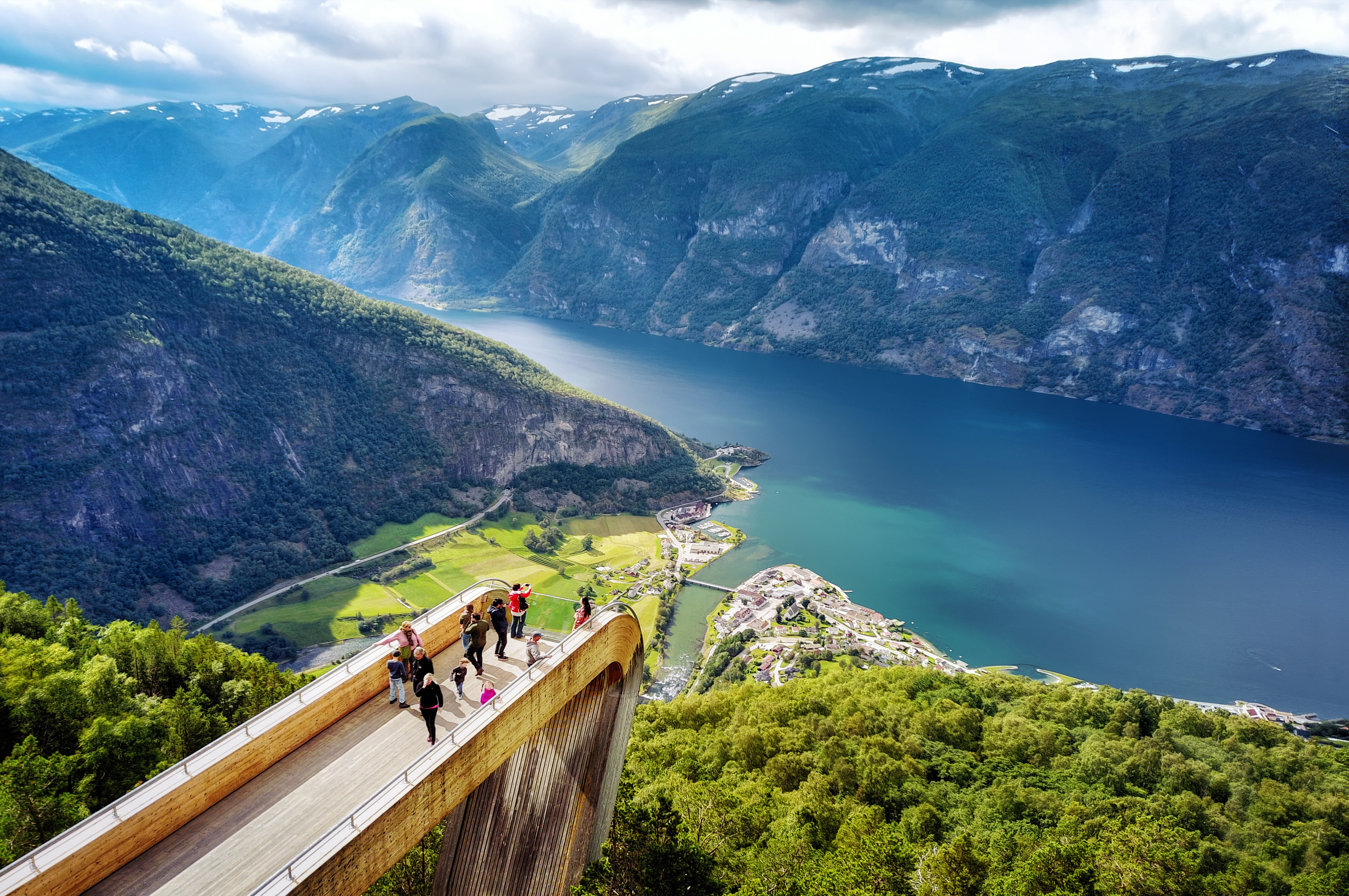 Smuk udsigt fra Stegastein udsigtspunktet over Aurlandsfjorden med grønne fjelde og den lille norske by Aurland nede ved vandet