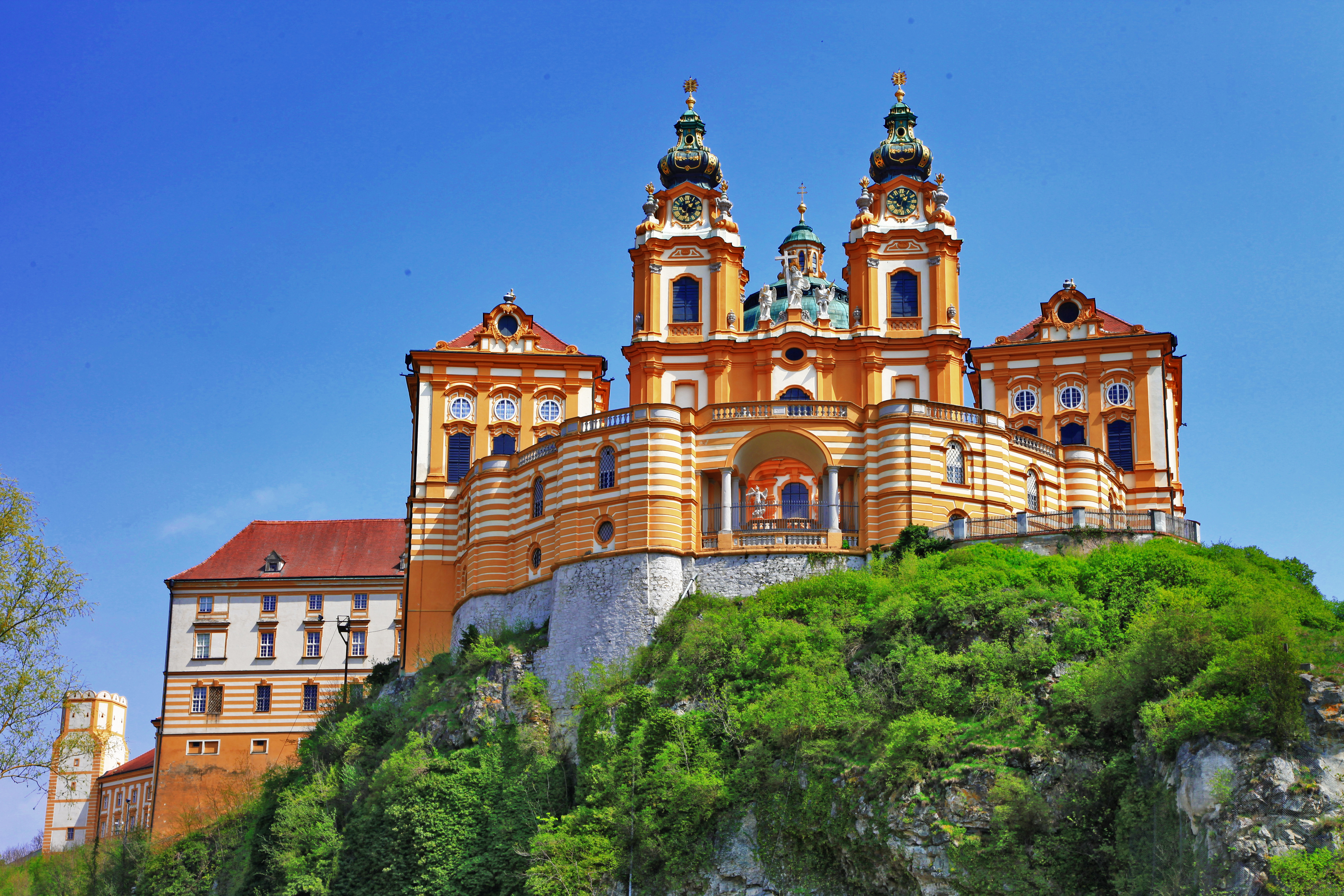 Stift Melk - det ikoniske barokkloster med orange facade og to tårne troner majestætisk på en klippe over Donaufloden i Østrig, et yndet rejsemål