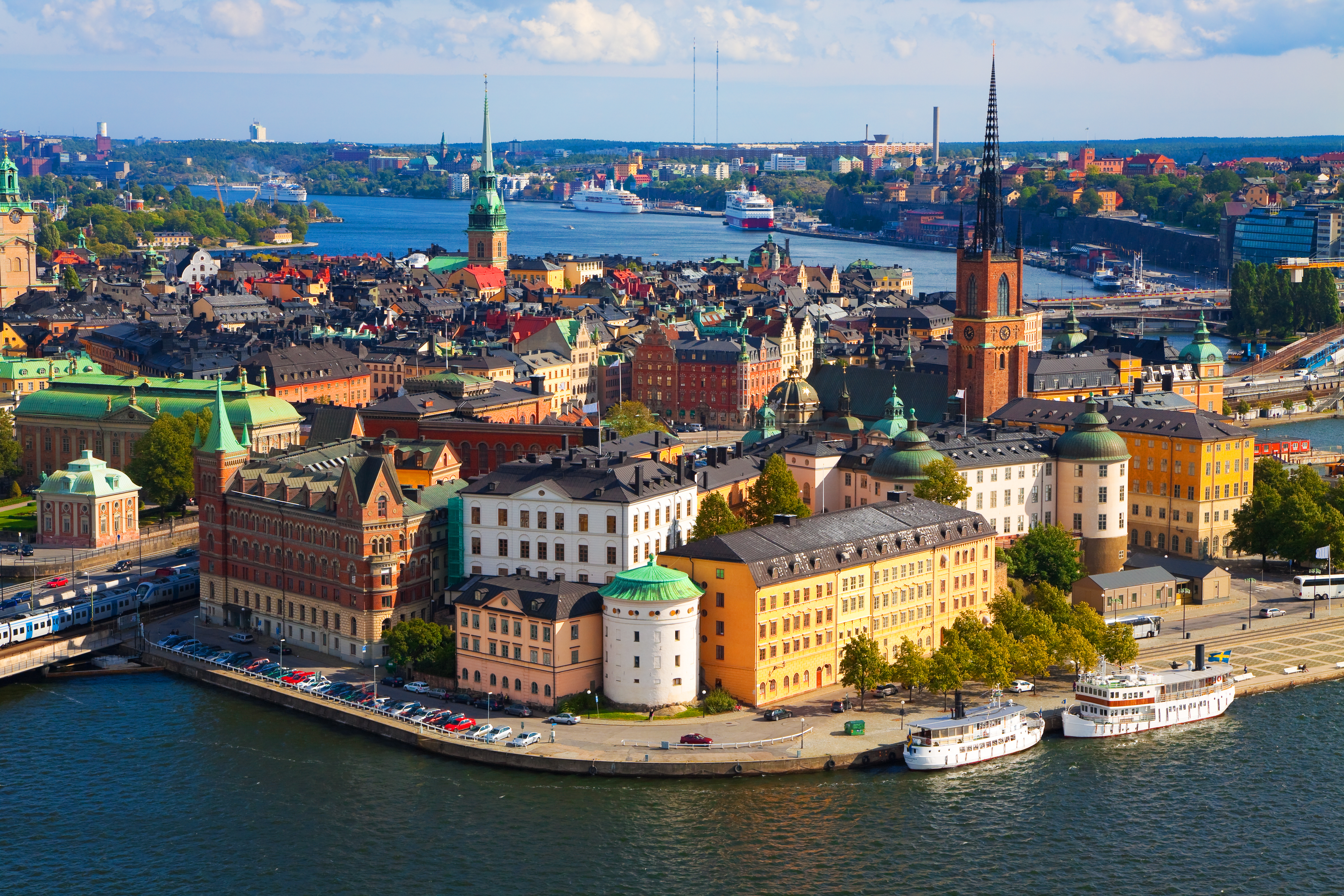 Det kongelige slot i Stockholm og Gamla Stan set fra oven med blå himmel og historiske røde tage
