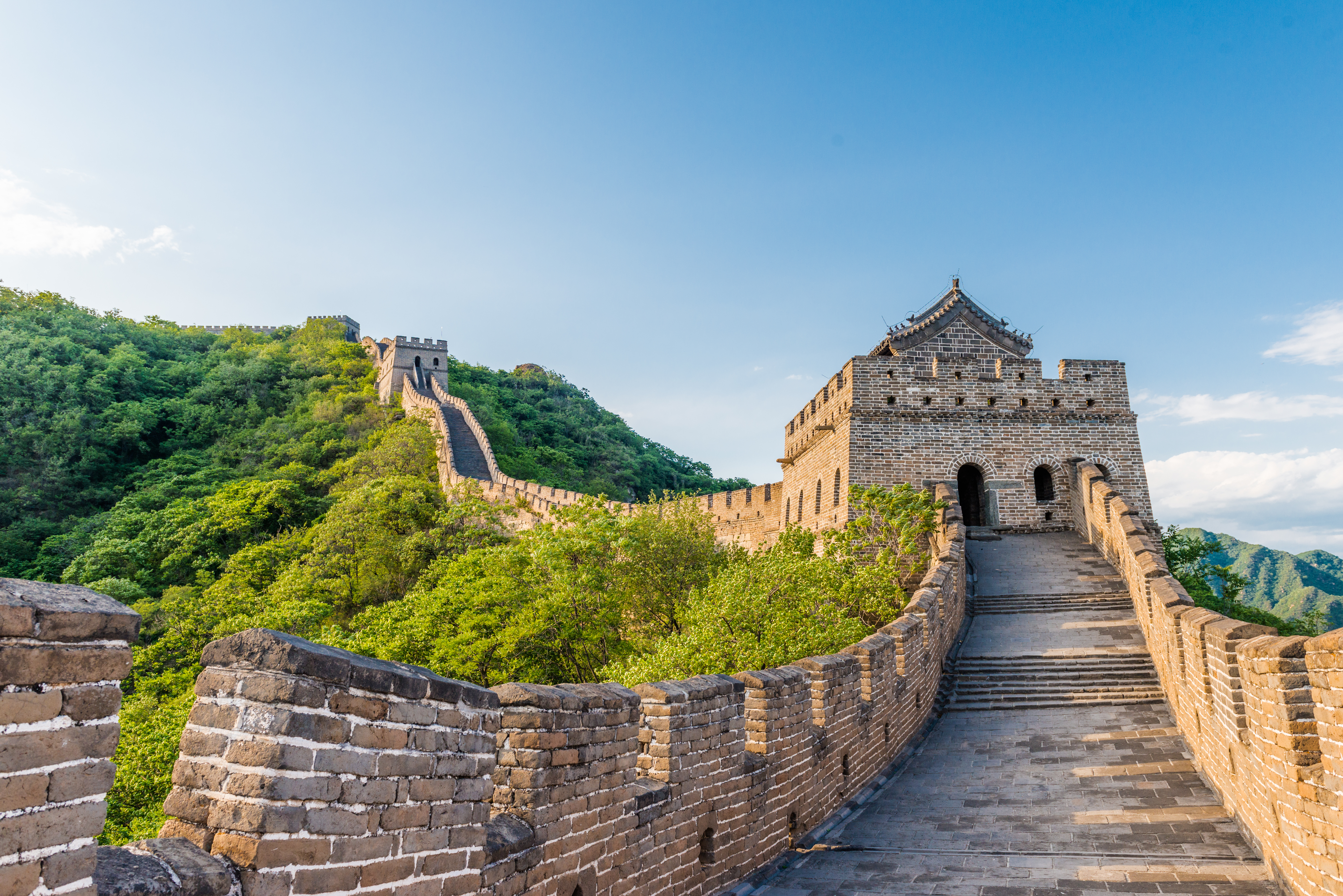 Den Store Kinesiske Mur ved Mutianyu strækker sig over grønne bjerge under en blå himmel nær Beijing