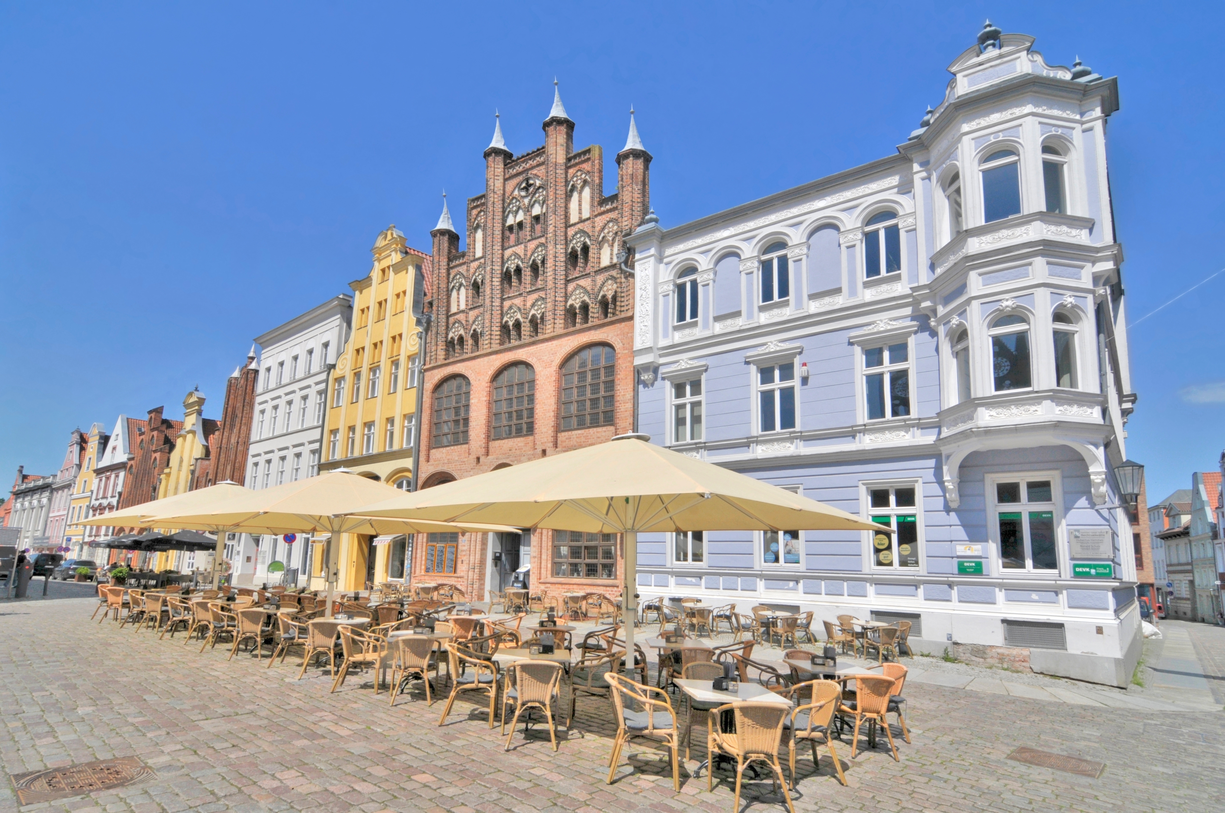 Smuk hanseatisk bymidte i Stralsund med middelalderlig arkitektur, gotiske teglstensbygninger og udendørs serveringssted på brosten
