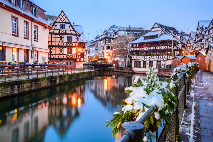 Farverige alsaciske bindingsværkshuse i snevejr ved floden i Strasbourg centrum