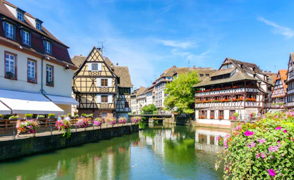Historiske farverige huse med blomster langs kanal i Strasbourg