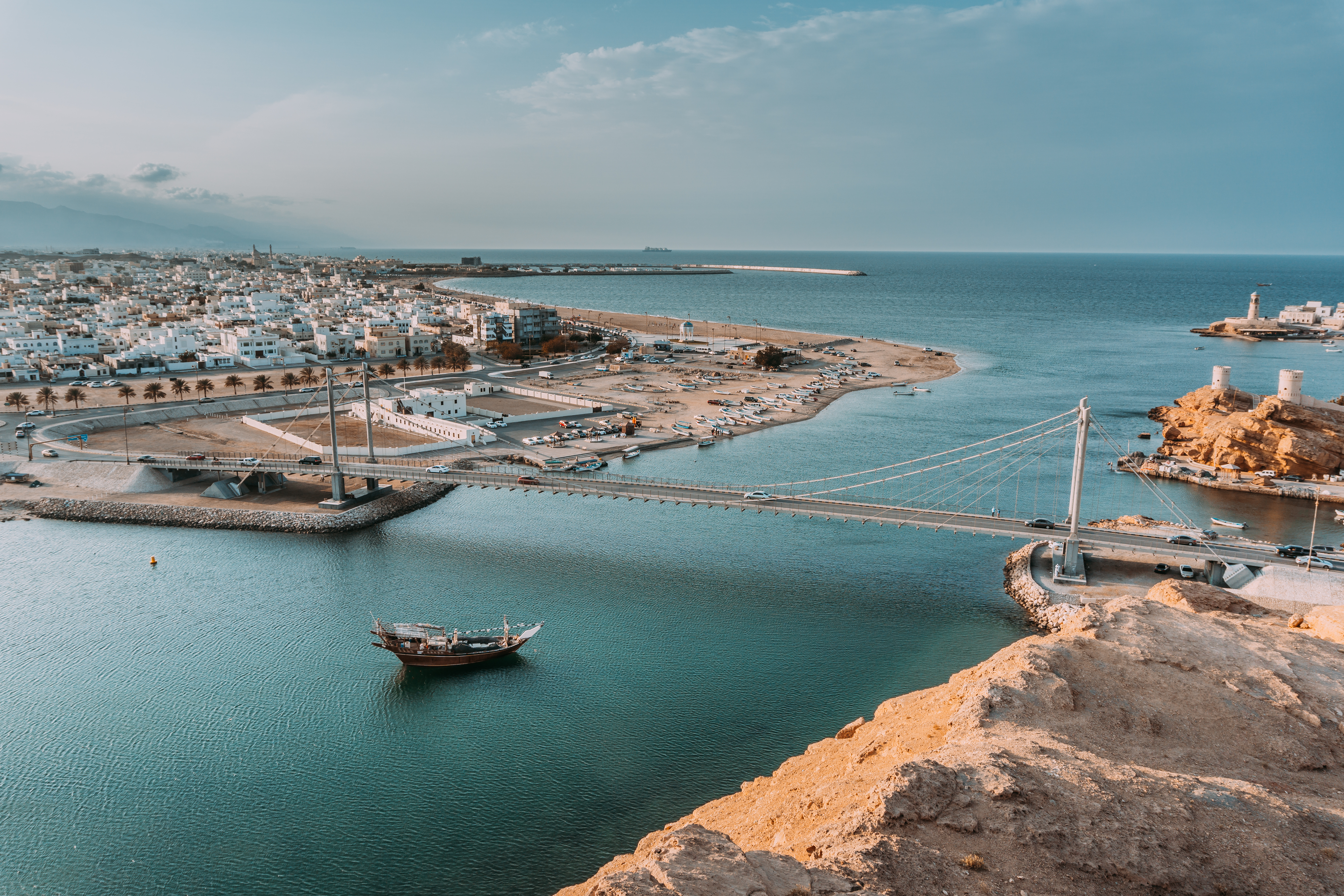 Fascinerende udsigt over Sur i Oman - en historisk havneby kendt for dhow-bådbyggeri med hvide bygninger og en imponerende bro over det klare hav