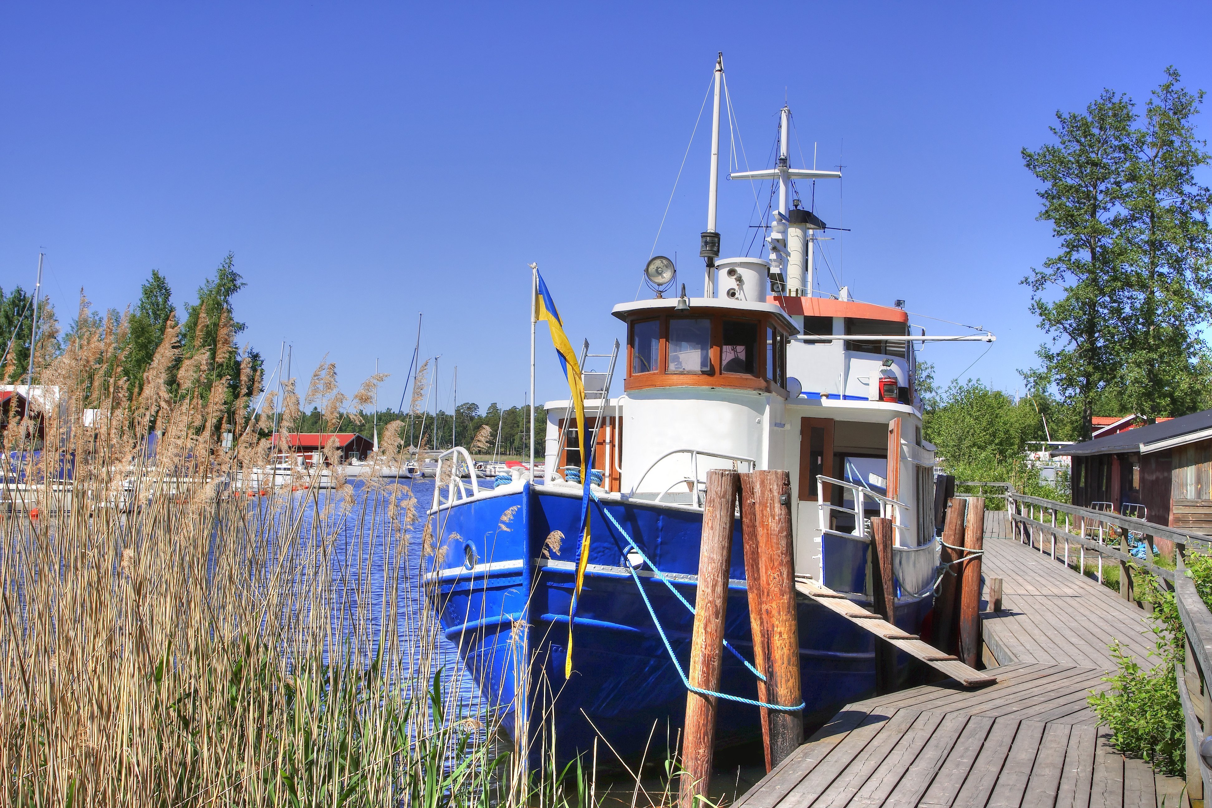 Idyllisk fiskerhavn ved Vättern søen i Karlsborg med blå både og træbro