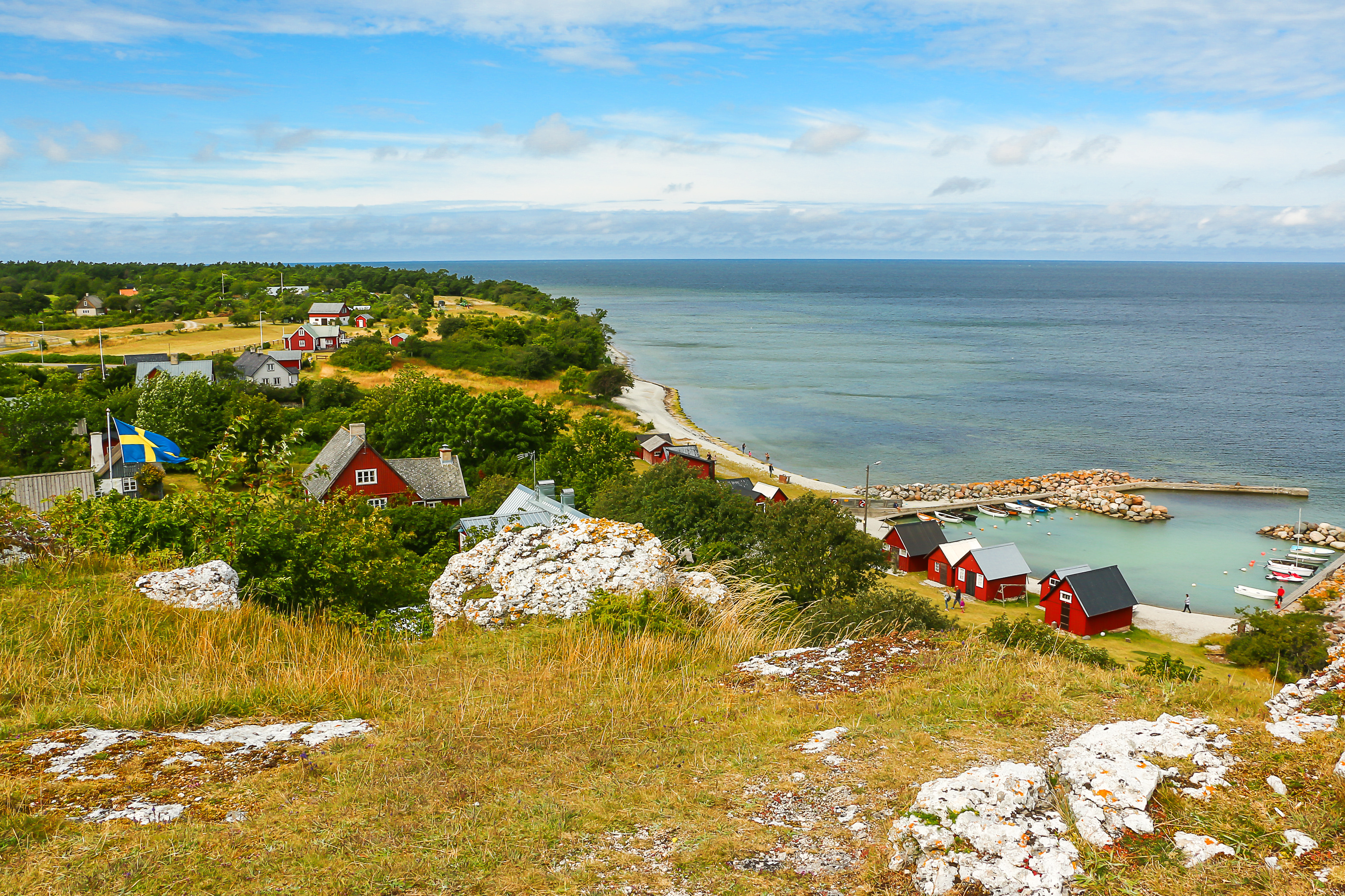 Svensk skærisland med karakteristiske røde huse, småbåde i havnen og kalkstensformation