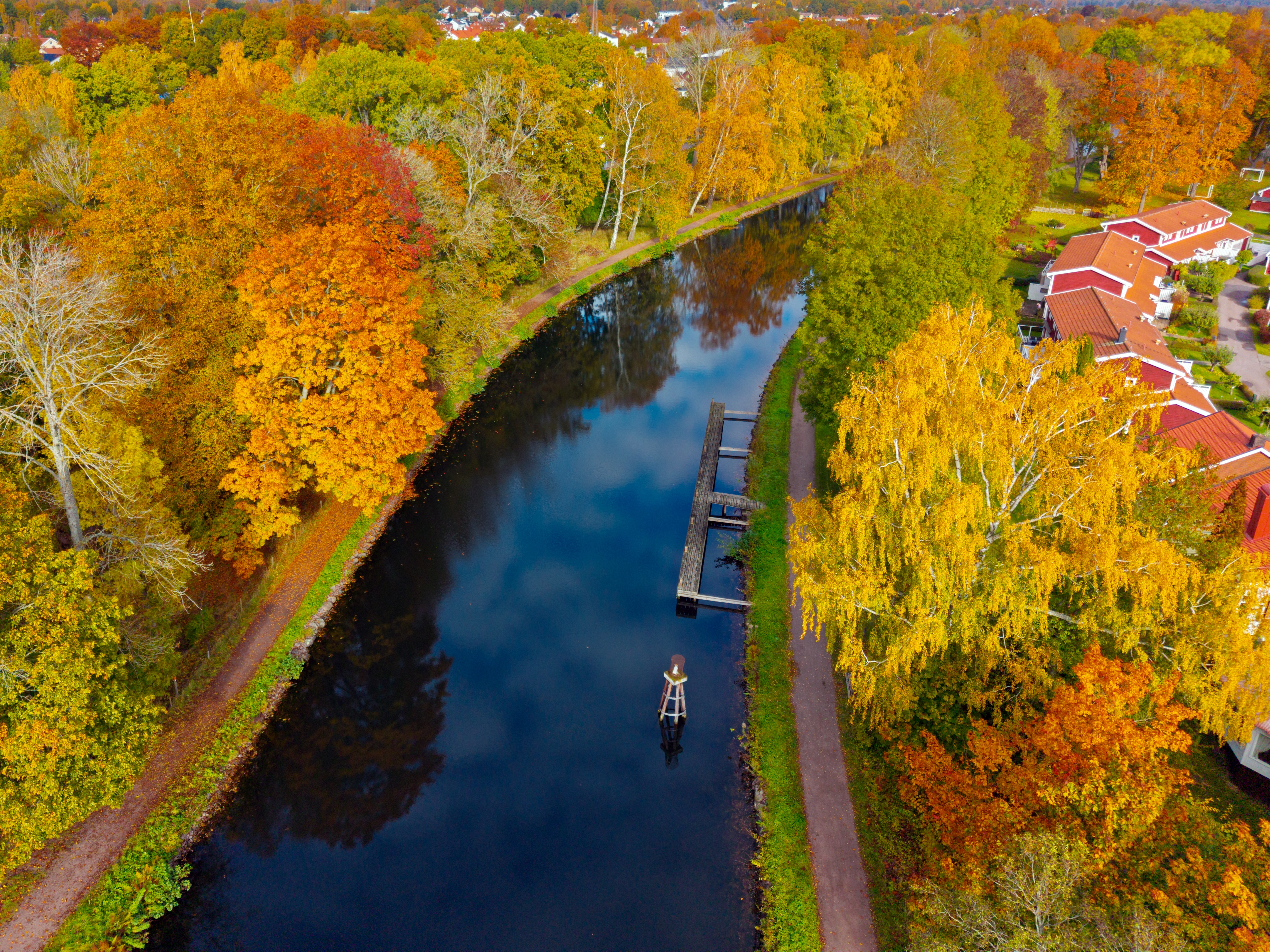 Luftfoto af den historiske Göta Kanal i Sverige omgivet af en farverig efteraarsskov med gyldne og orange blade