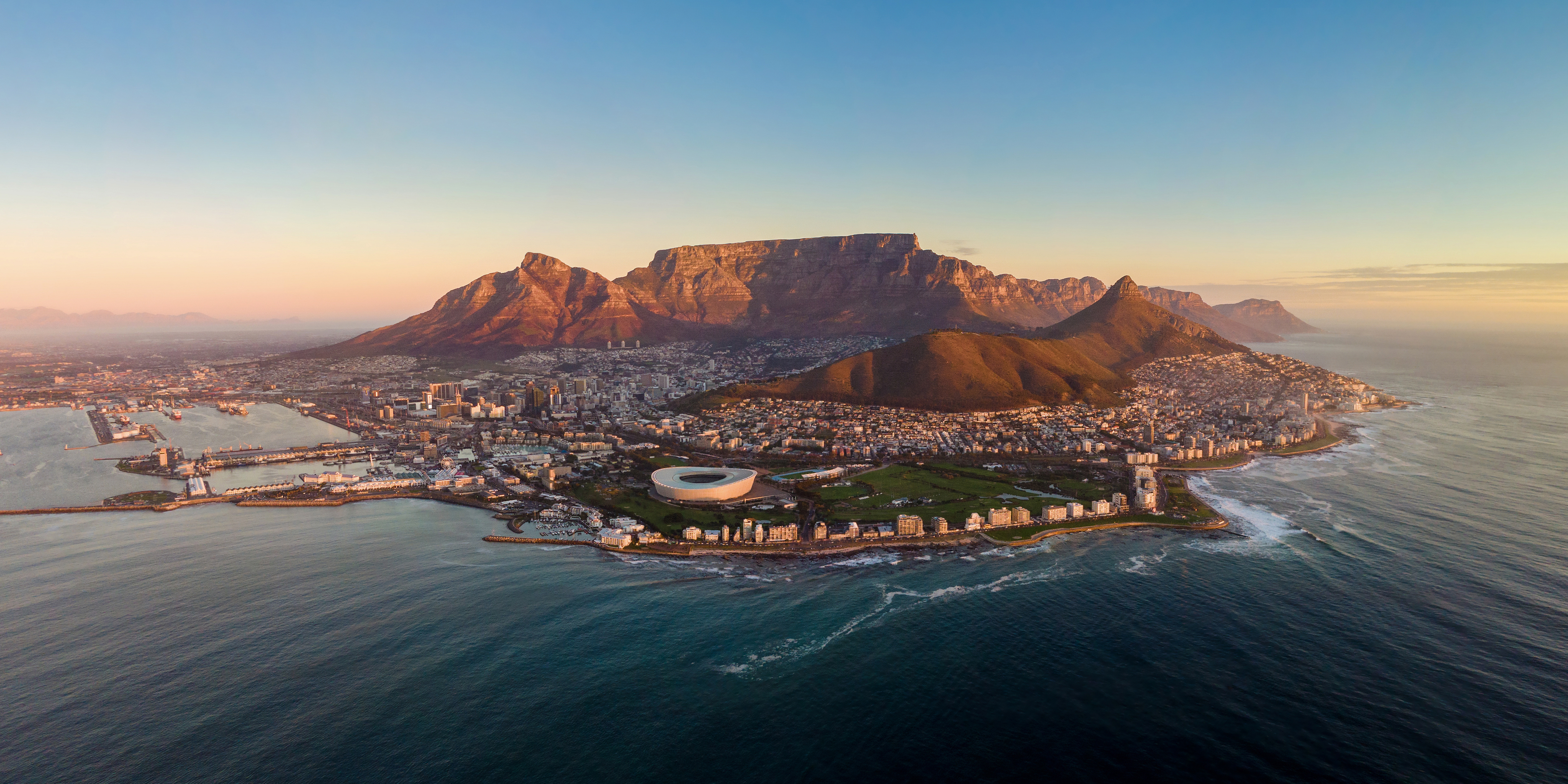 Majestætisk udsigt over Cape Town med det ikoniske Table Mountain og havet ved solnedgang, Sydafrika