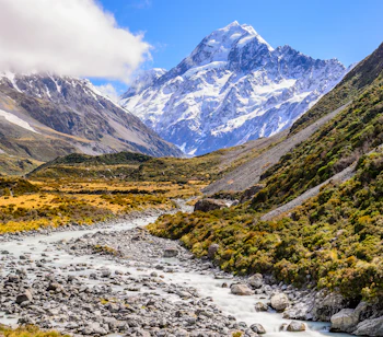 Spektakulært bjerglandskab ved Mount Cook med vandløb gennem gylden dal i New Zealand