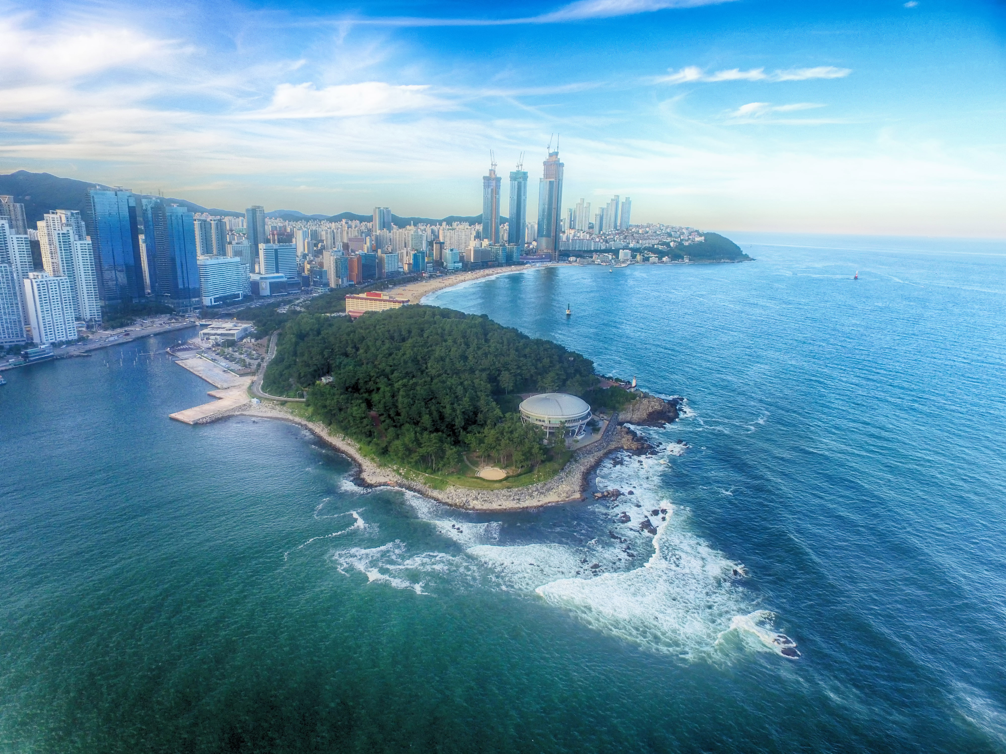 Fantastisk udsigt over Busans kystlinje ved Haeundae i Sydkorea med azurblåt hav, moderne skyskrabere og lystbåde i sommersolskin