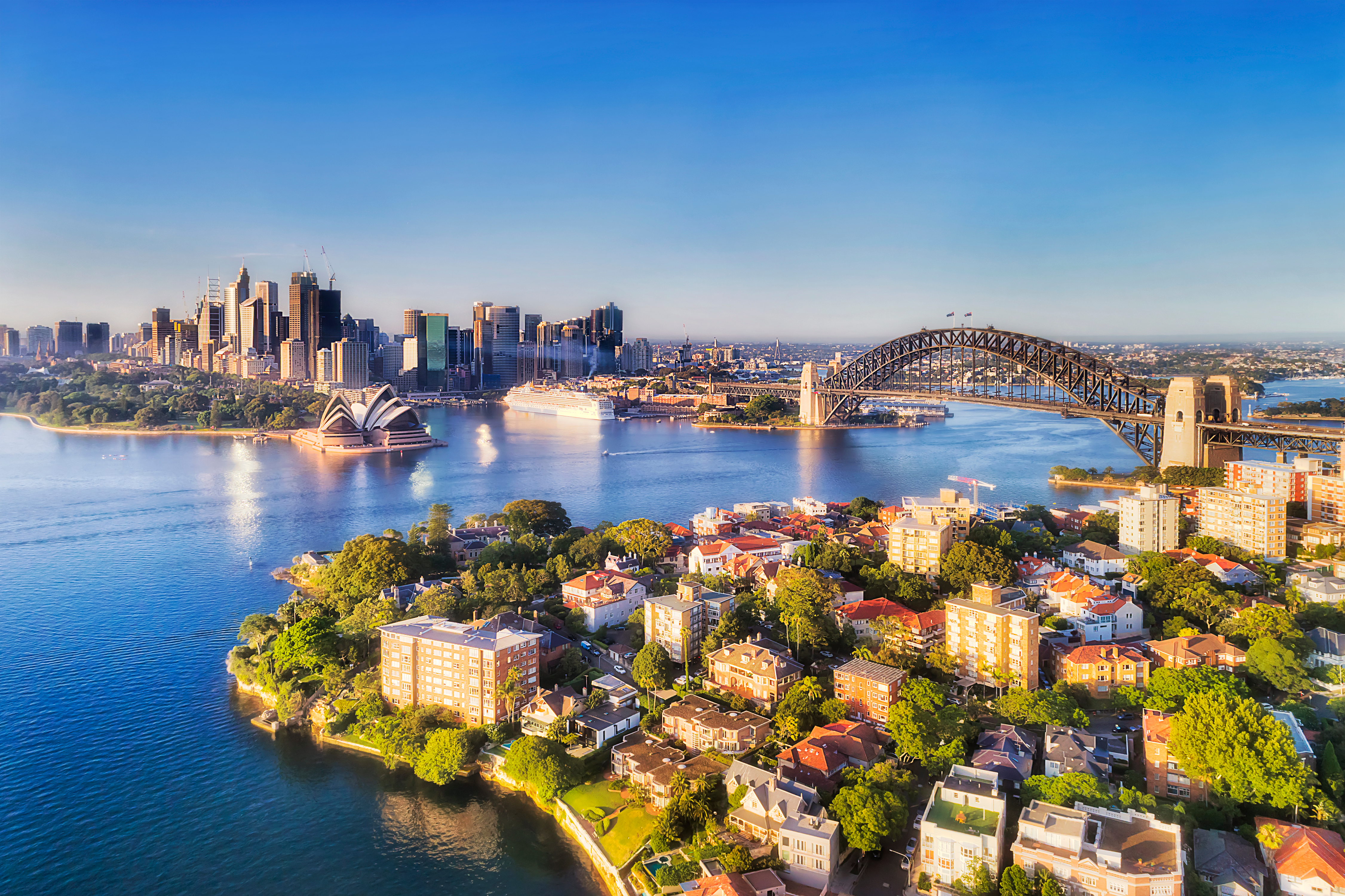 Fascinerende luftfoto af Sydneys havnefront med den ikoniske Harbour Bridge, der elegant forbinder byens travle CBD med de grønne, velstående North Shore-områder, et must-see landemærke på enhver rejse til Australien
