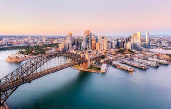 Sydney Opera House og havnebroen i smukt morgenlys med skyline