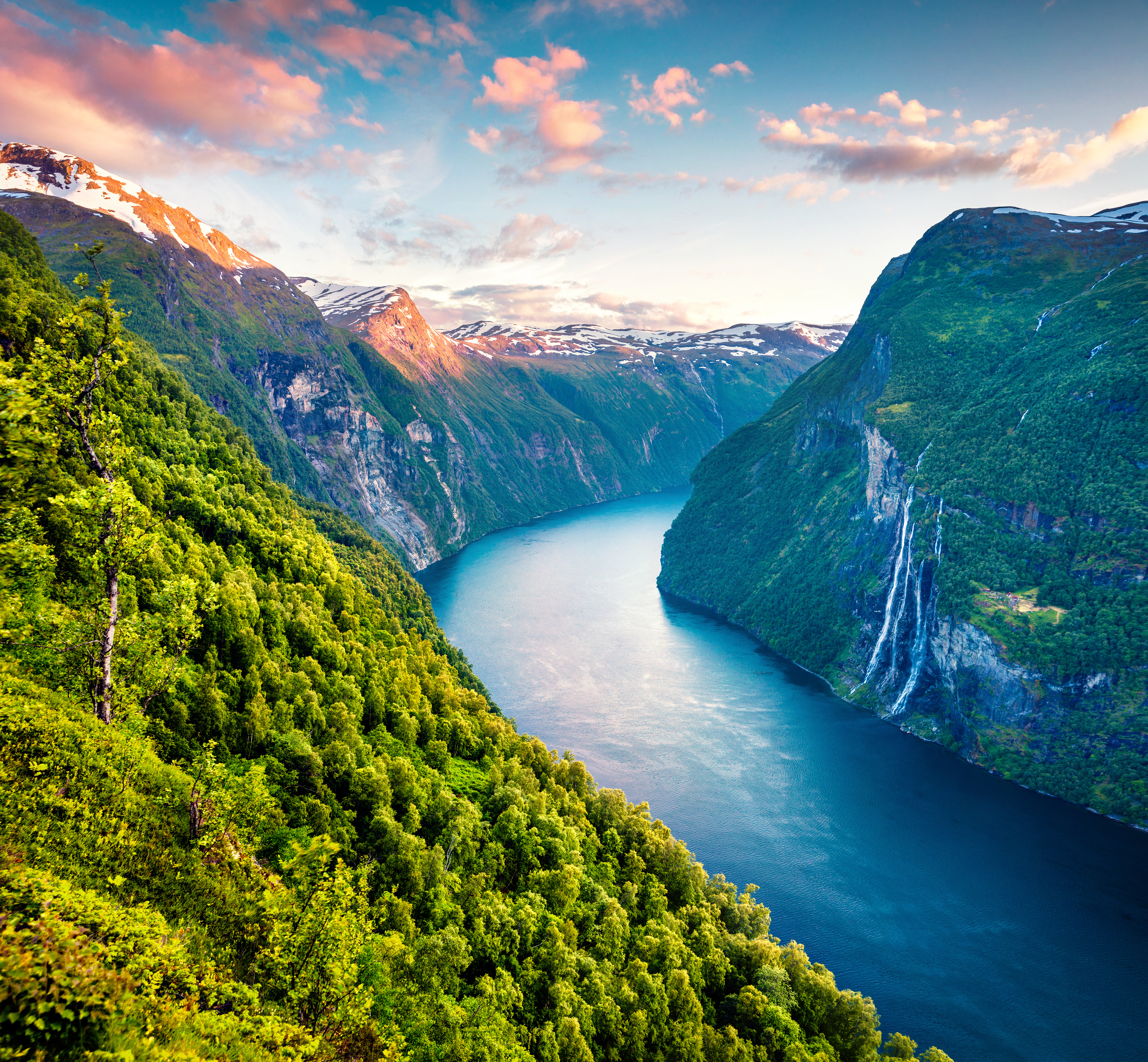 Fascinerende luftbillede af Sunnylvsfjorden nær Geiranger i solnedgangslys, der fremhæver det dramatiske fjordlandskab og de ikoniske Syv Søstre vandfald