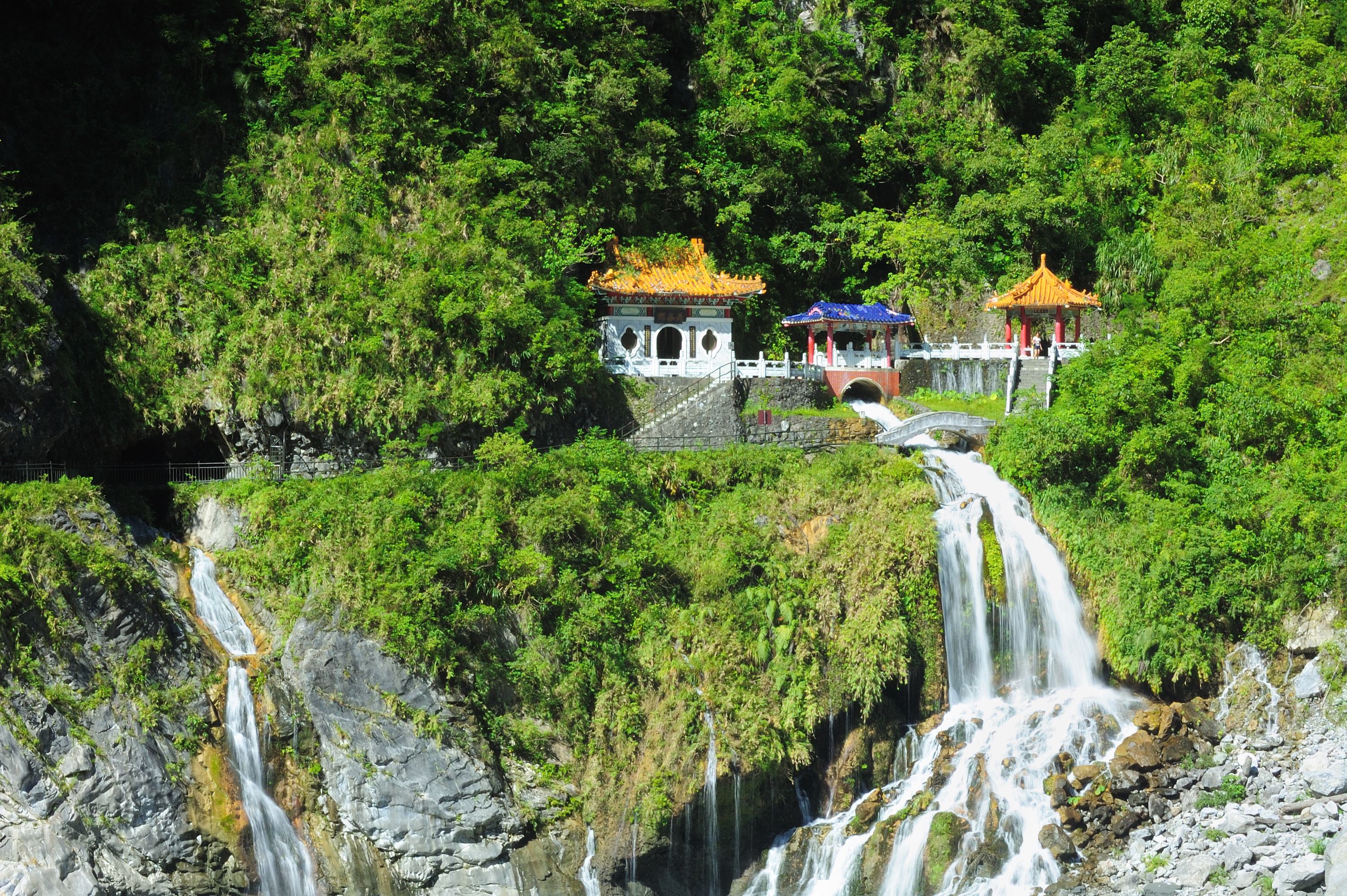 Traditionelt kinesisk tempel med pagode-tage ved dramatisk vandfald i Taiwans regnskov