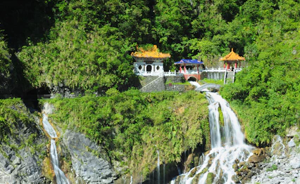 Traditionelt kinesisk tempel med pagode-tage ved dramatisk vandfald i Taiwans regnskov