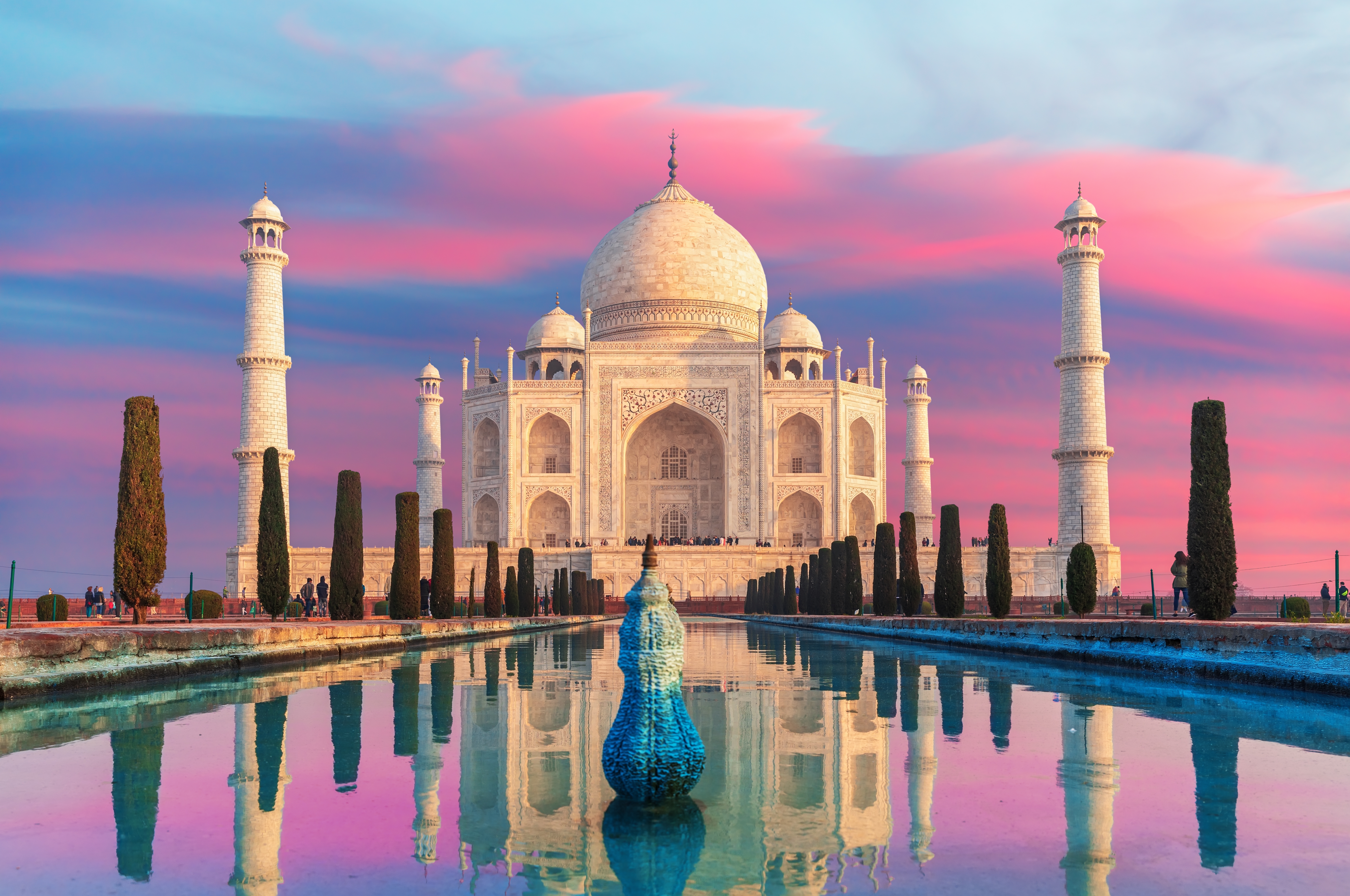 Det imponerende Taj Mahal badet i solnedgangens lyserøde skær med spektakulær spejling i vandet, en UNESCO verdensarv i Agra