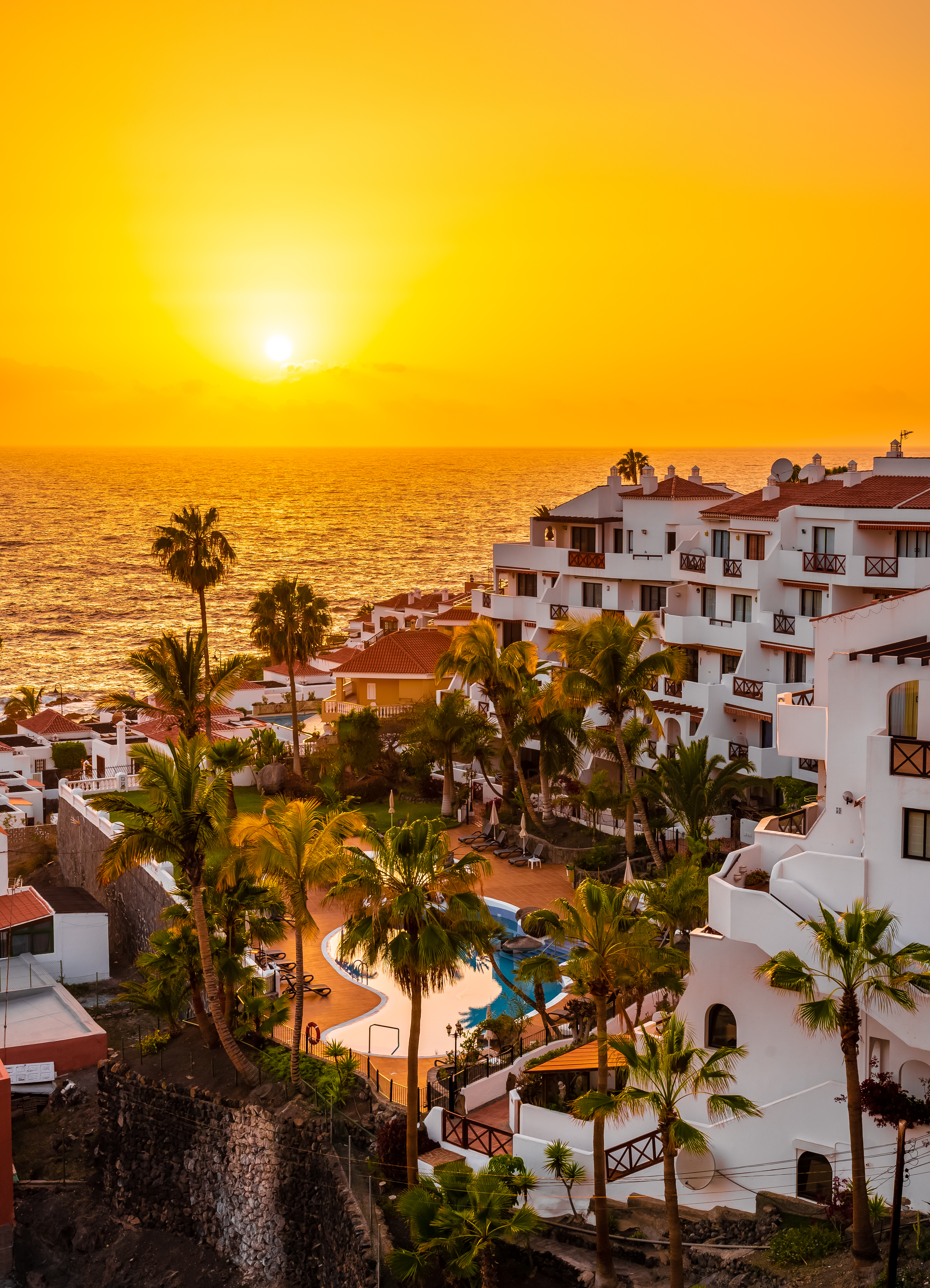 Malerisk solnedgang over kystlinjen ved Los Gigantes på Tenerife med luksuriøse ferieresorts og udsigt over Atlanterhavet
