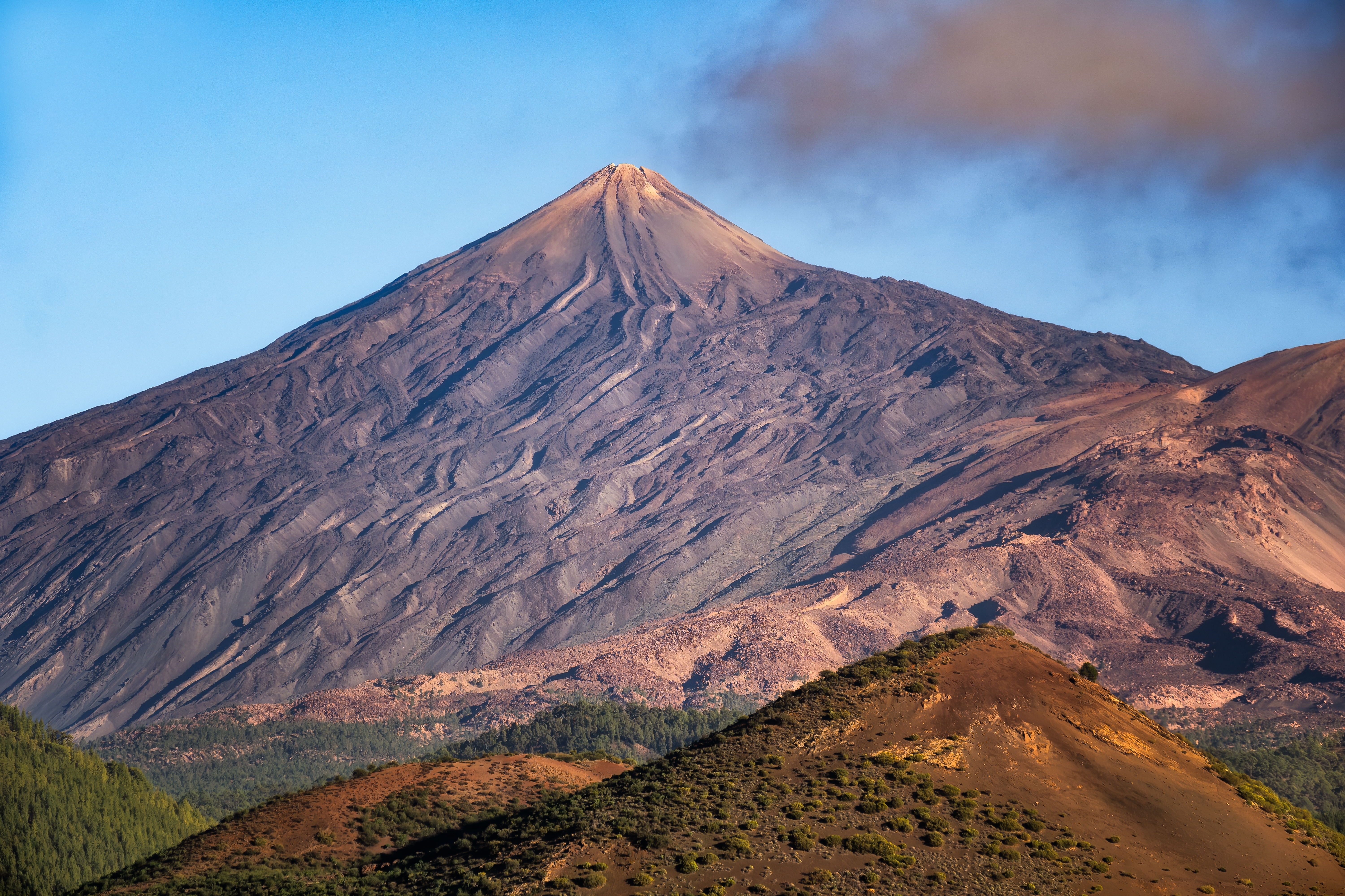 Betagende landskabsudsigt over vulkanen Teide på Tenerife, hvis markante silhuet rejser sig over det rødbrunlige vulkanske terræn i nationalparken - et must-see naturfænomen på De Kanariske Øer