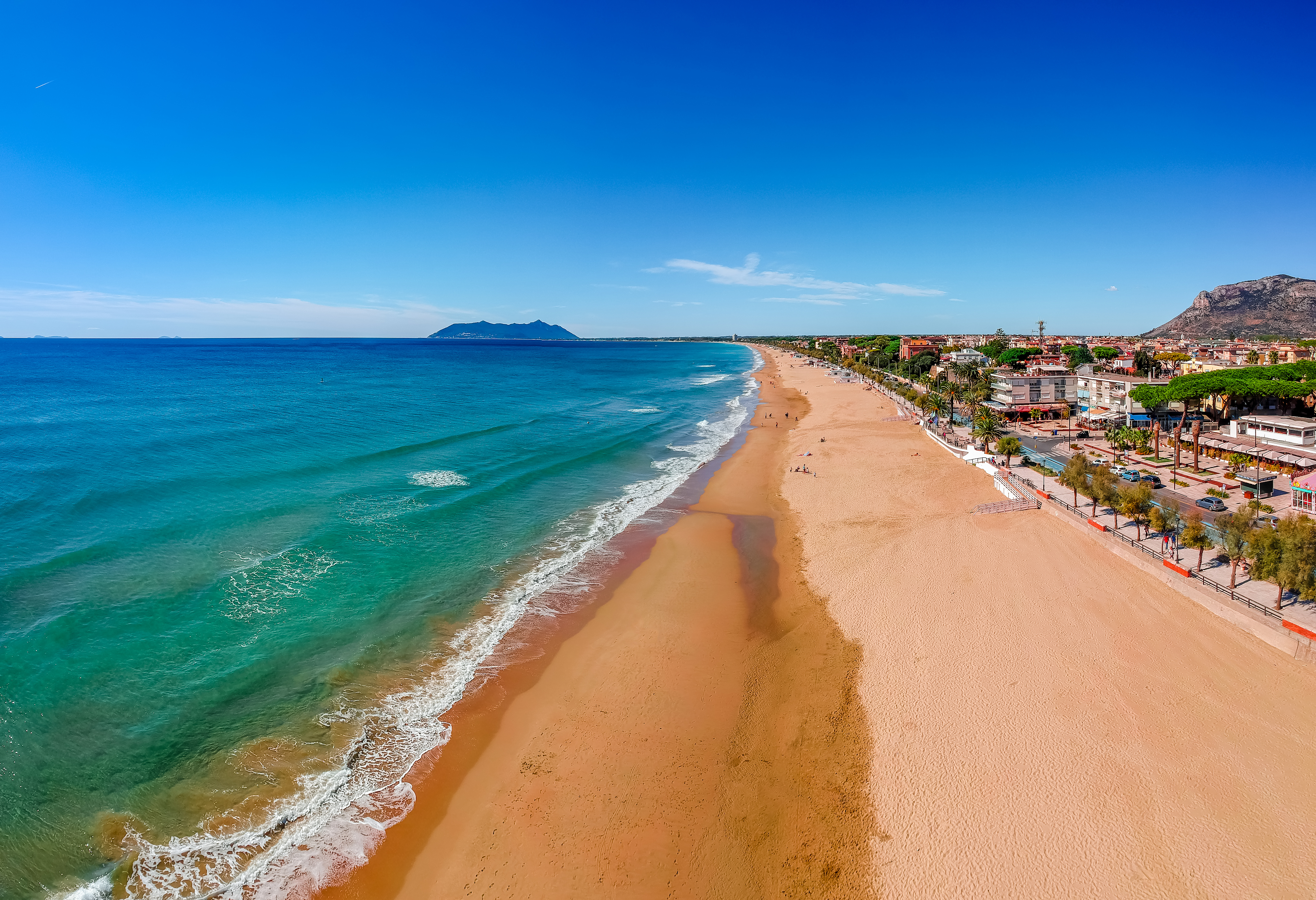 Smuk luftudsigt over Terracinas gyldne sandstrand og det turkisblå Middelhav med byens promenade og palmer i Lazio, Italien