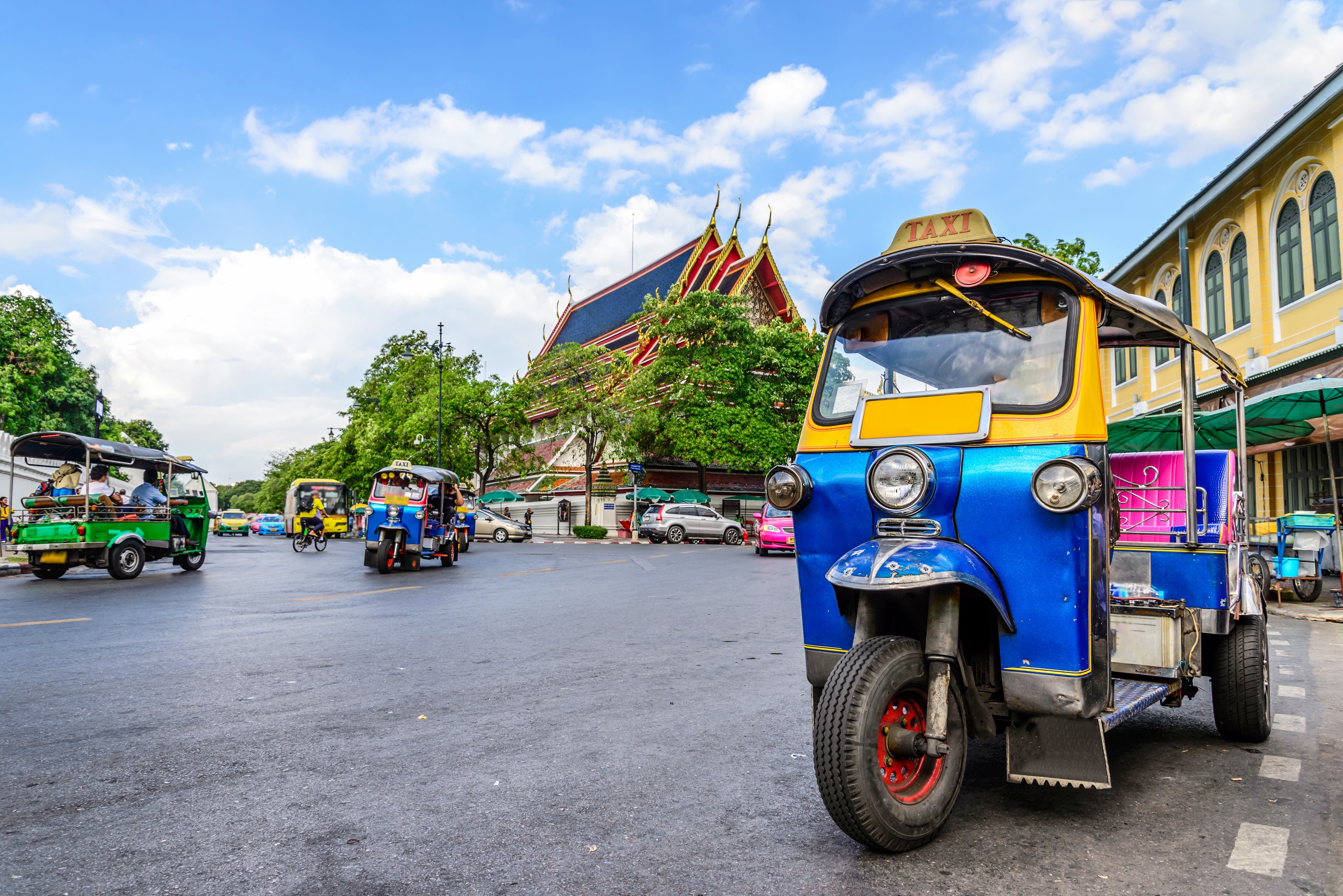 Traditionel tuk-tuk taxi på bangkok gade med tempel i synsfeltet