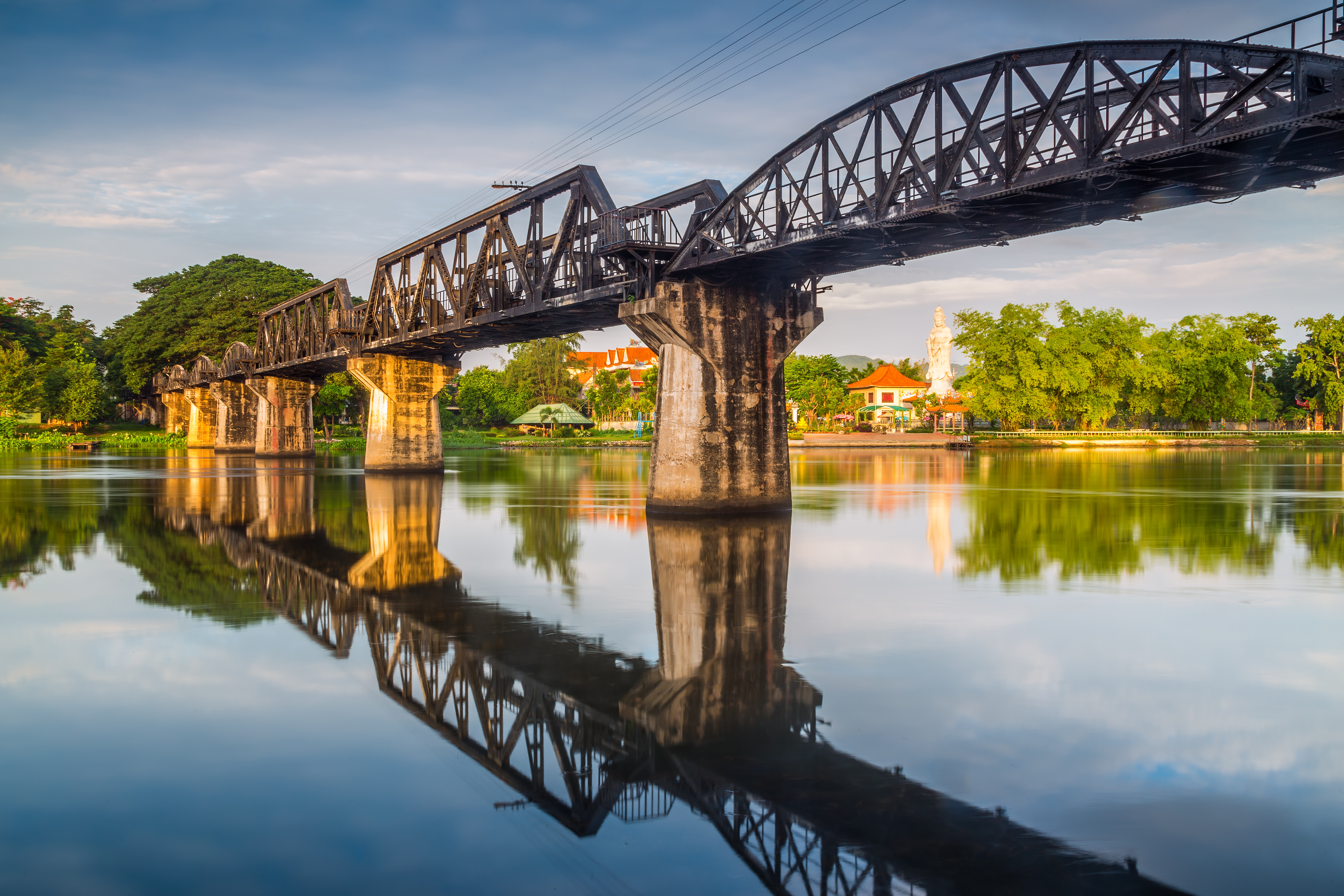 Den historiske bro over River Kwai i Thailand med smuk vandspejling