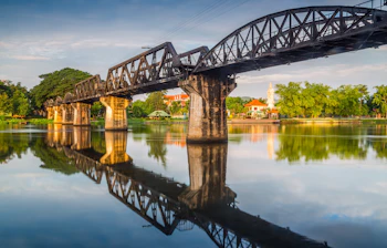 Den historiske bro over River Kwai i Thailand med smuk vandspejling