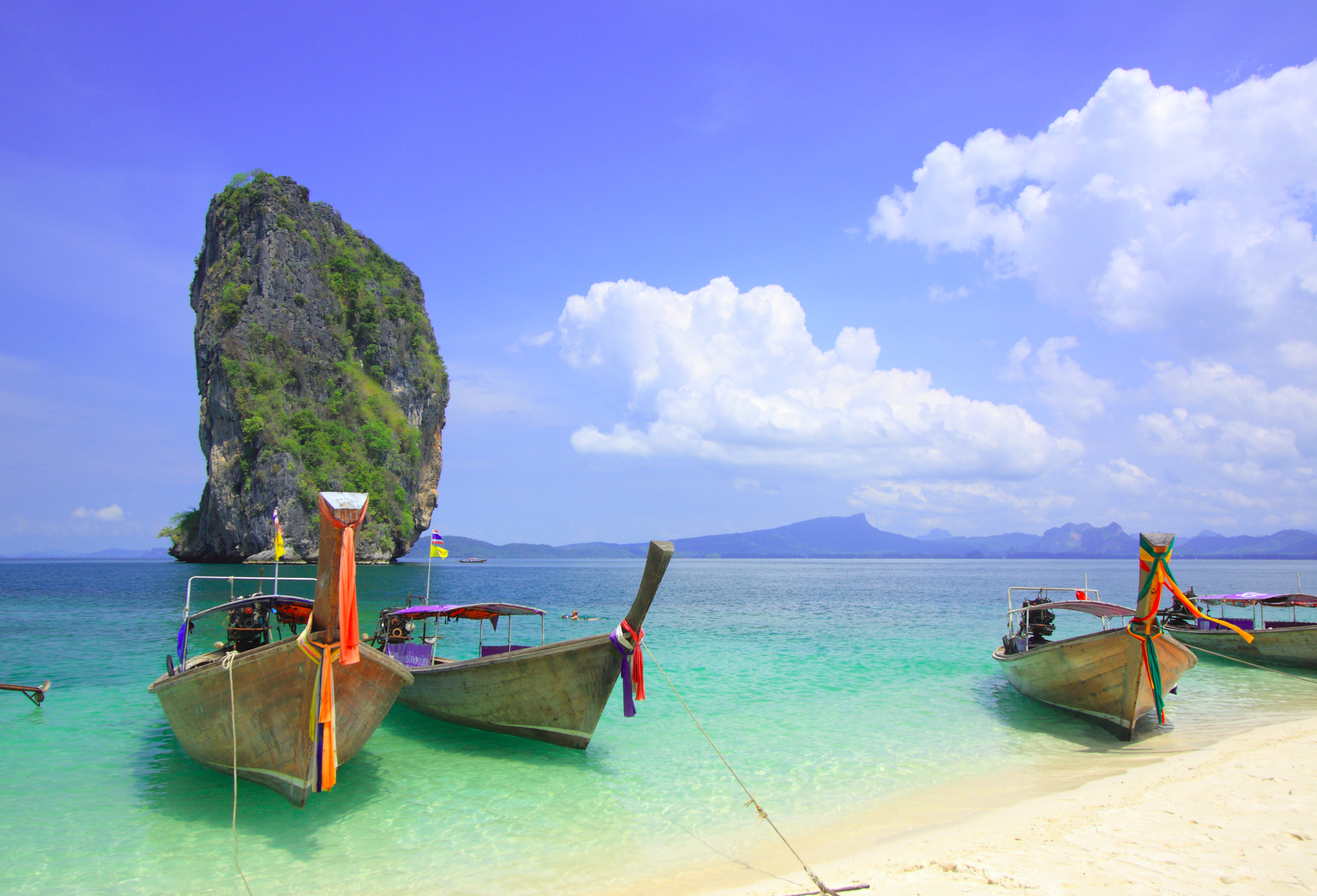 Tropiske longtail både forankret ved paradisisk strand i Krabi Thailand med krystalklart vand og blå himmel