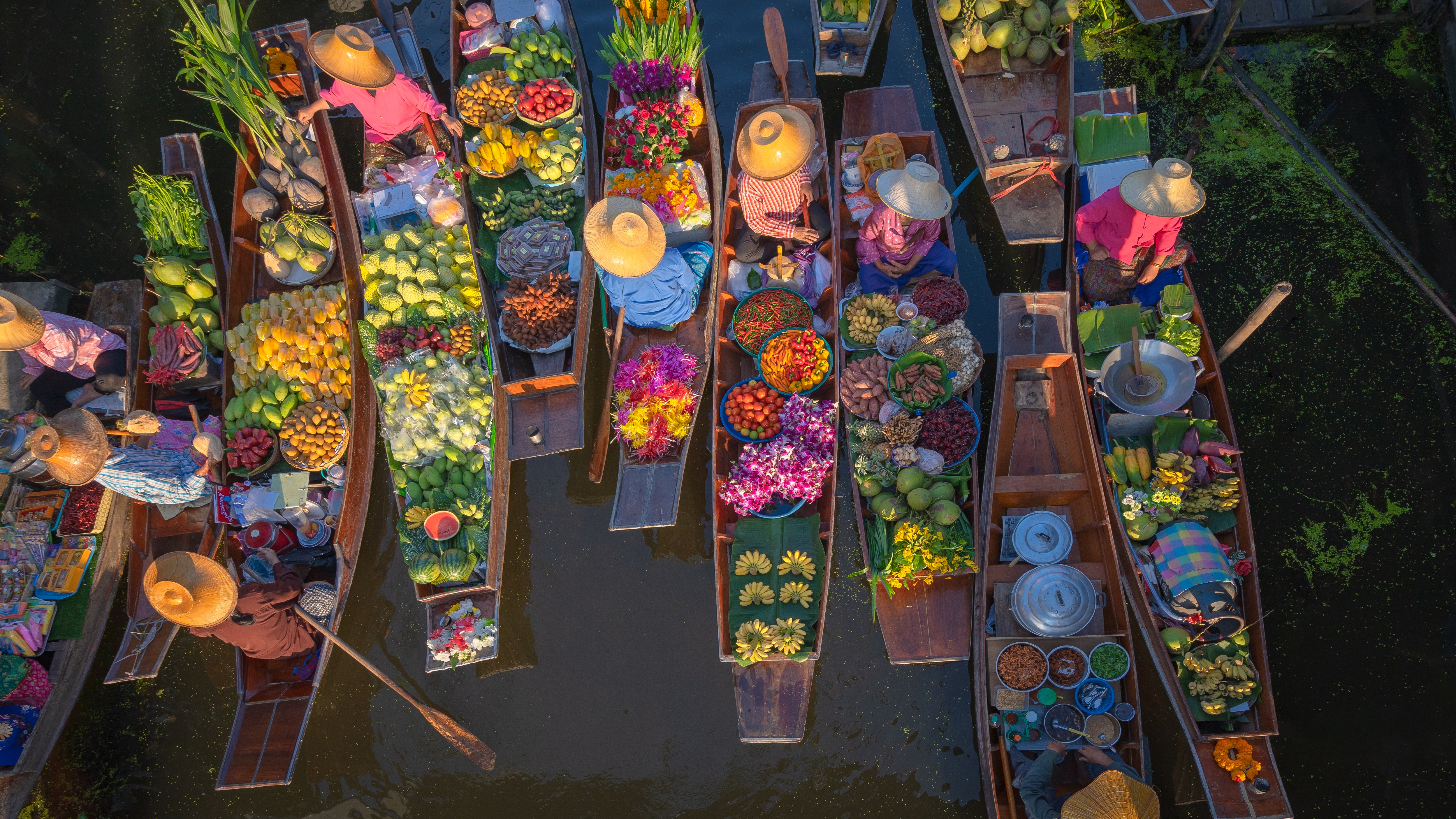 Luftfoto af det traditionelle flydende marked Damnoen Saduak i Thailand med farverige både lastet med tropiske frugter blomster og grøntsager