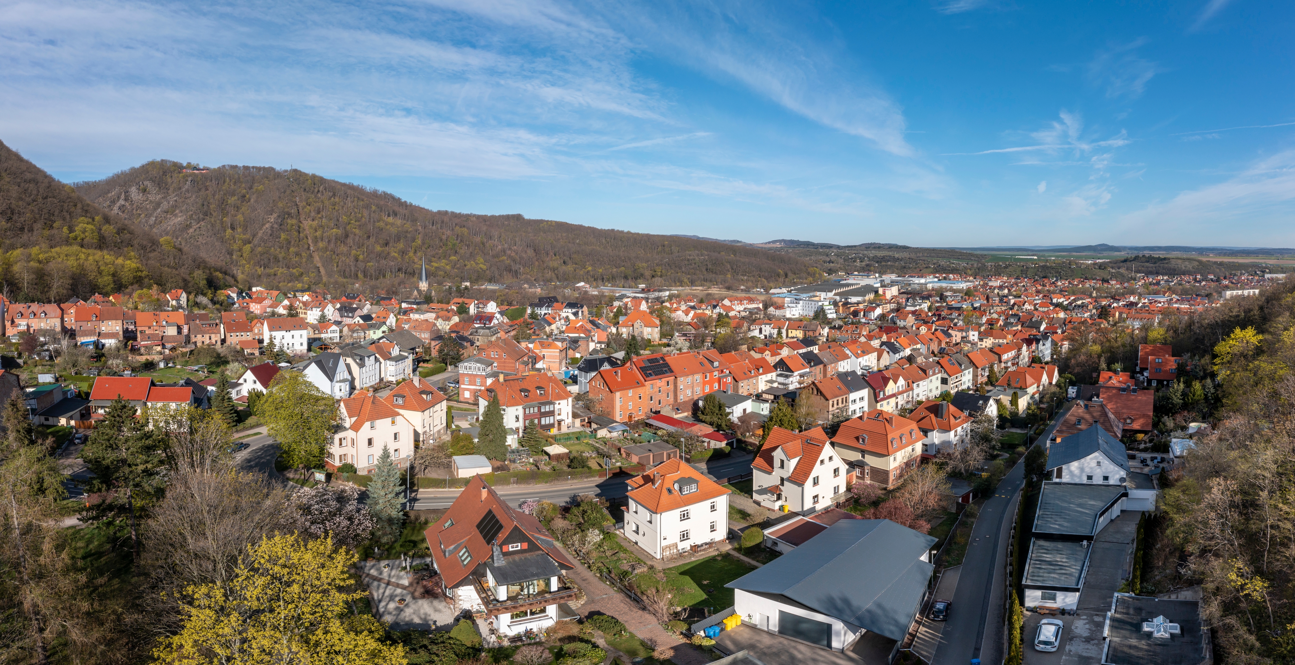 Smukt luftfoto af Thale by i Harzen, Tyskland, med typiske røde tage, grønne bjerge og klart blå forårshimmel