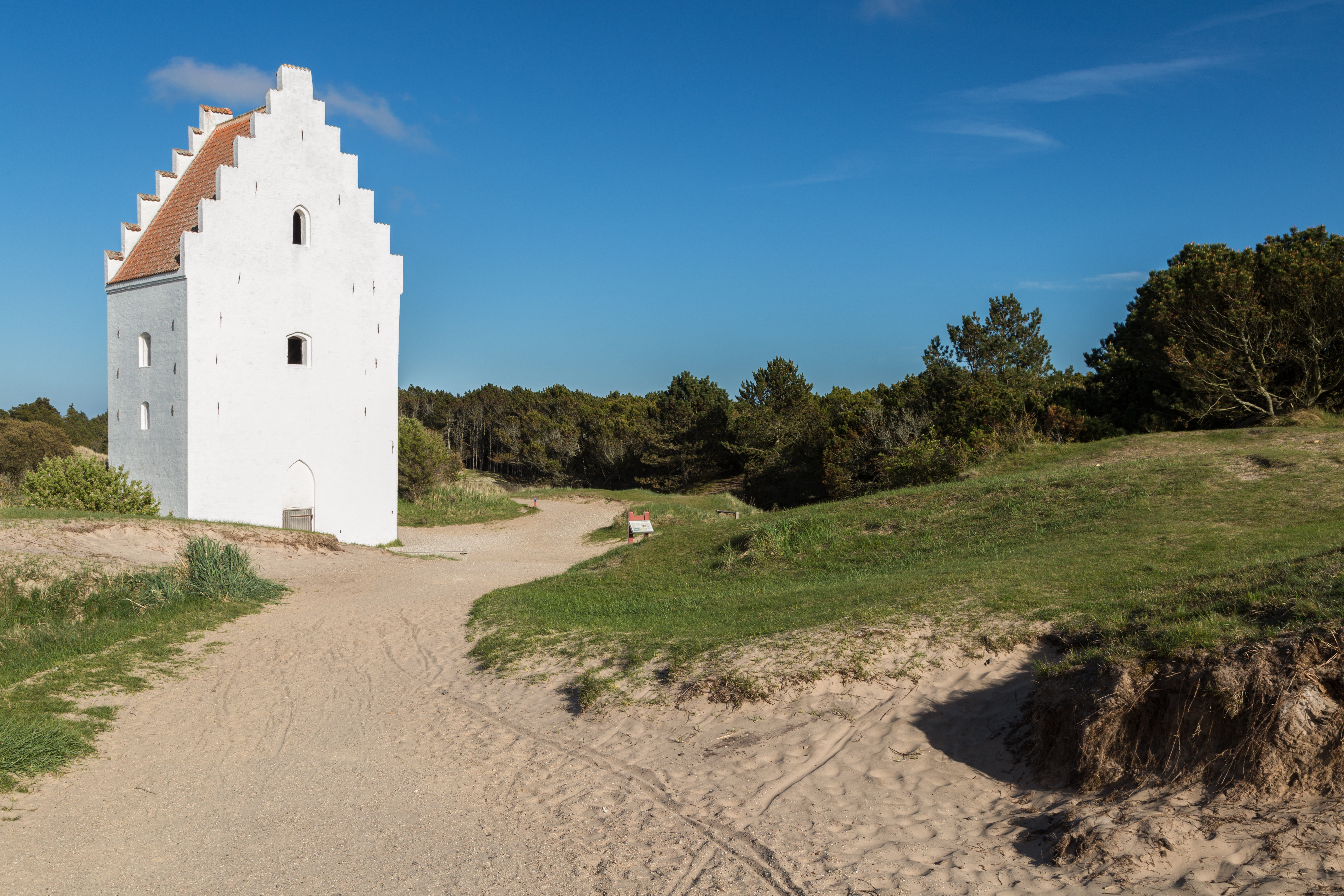 Charakteristisk hvid kirke i klitlandskabet ved Skagen under klar blå himmel