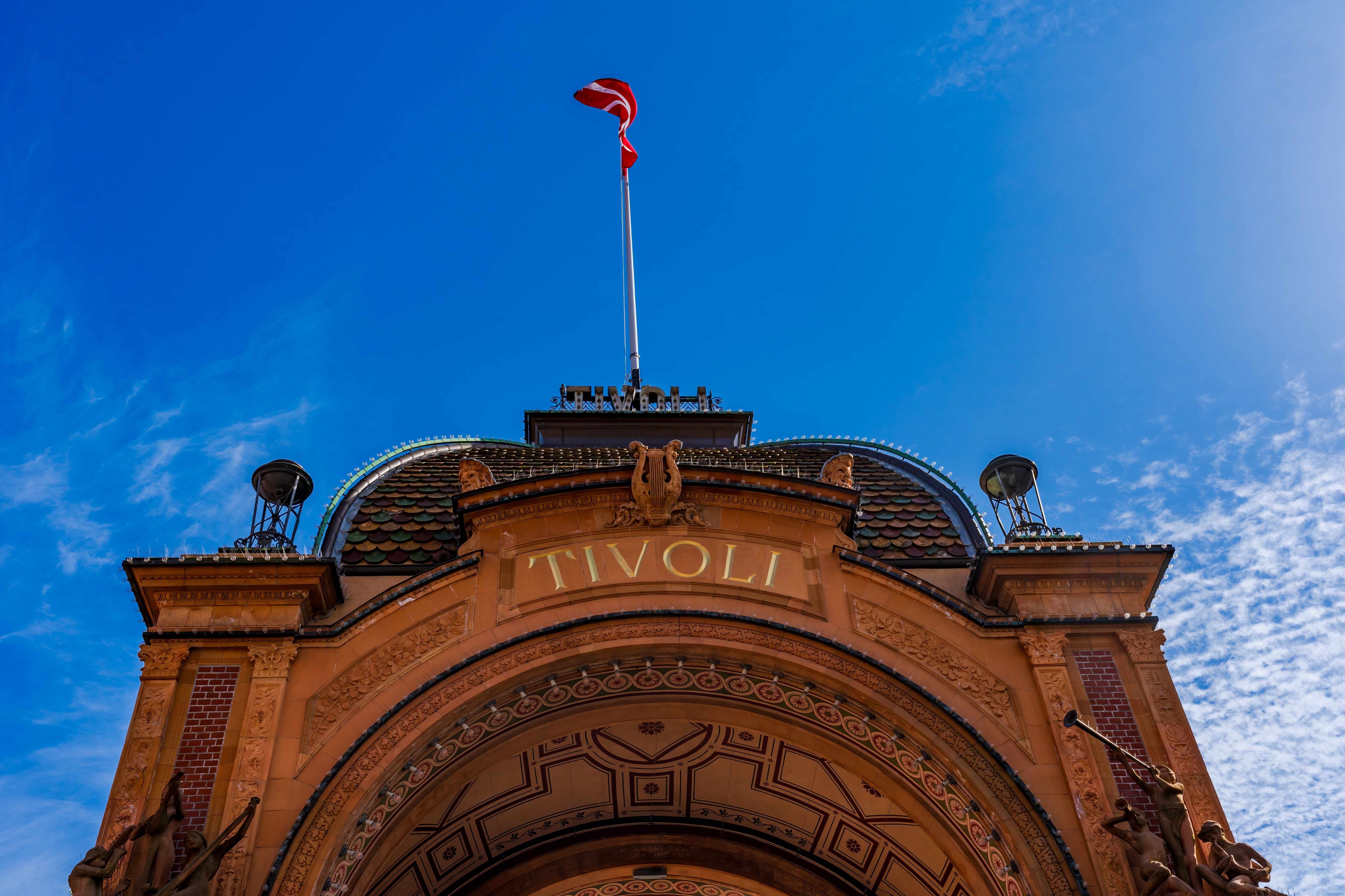 Indgangsporten til det verdenskendte Tivoli Gardens i København, Danmark, med Dannebrog og blå himmel