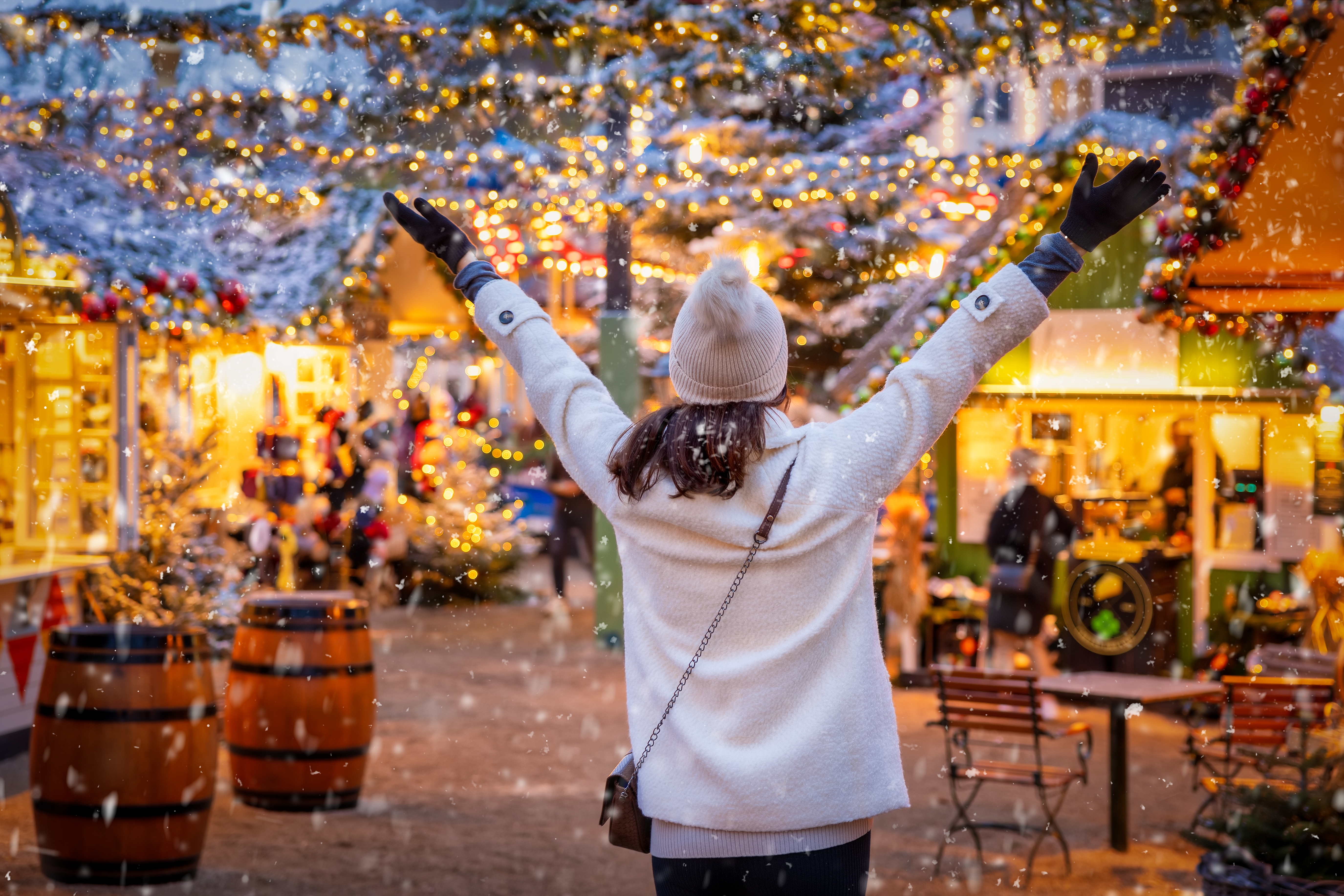 Kvinde jubler på Tivolis julemarked med gyldne lys og vintervejr