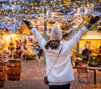 Kvinde jubler på Tivolis julemarked med gyldne lys og vintervejr