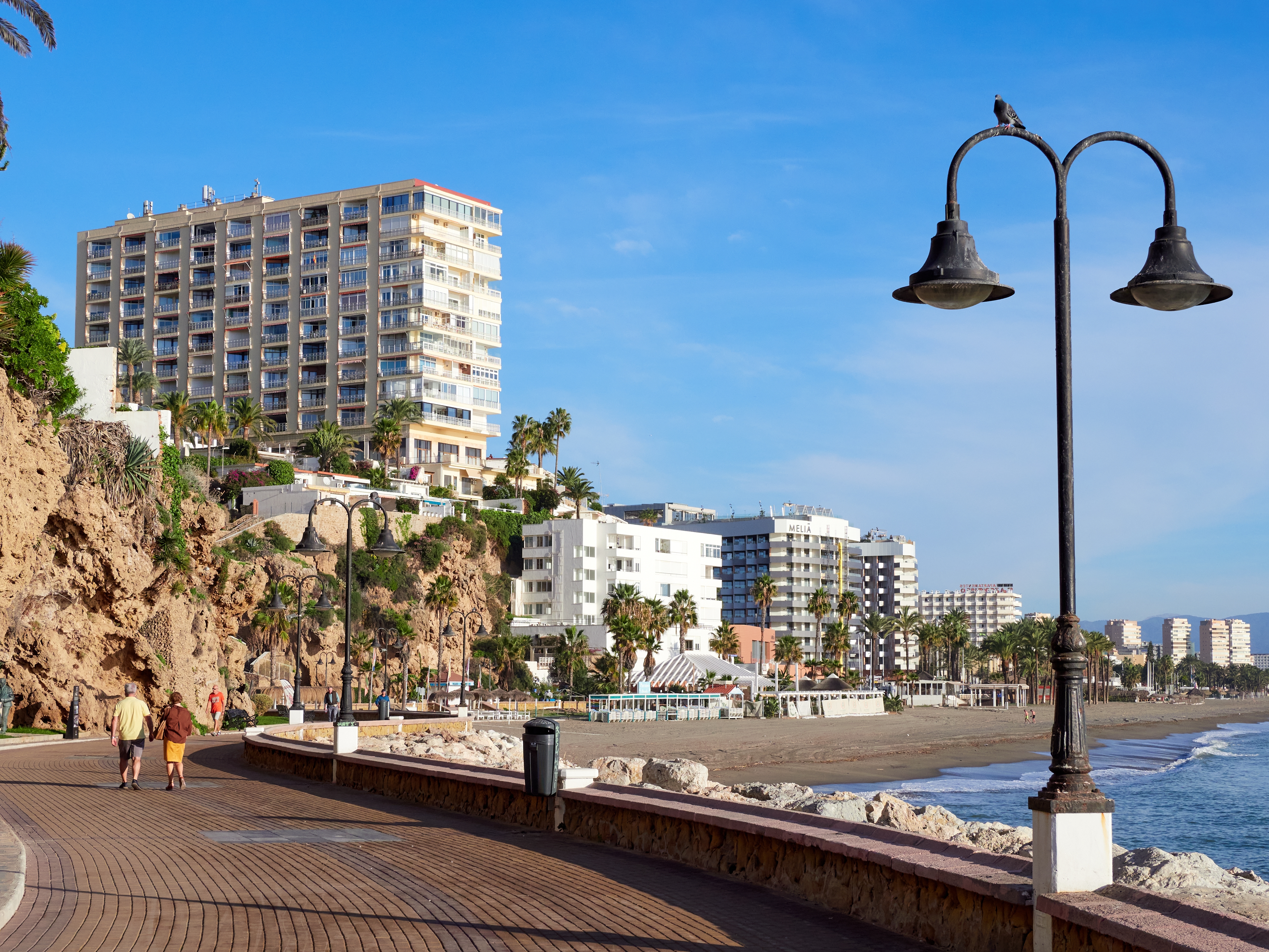 Dejlig kystpromenade langs Carihuela stranden i Torremolinos med palmer og hotelkomplekser ved Middelhavet