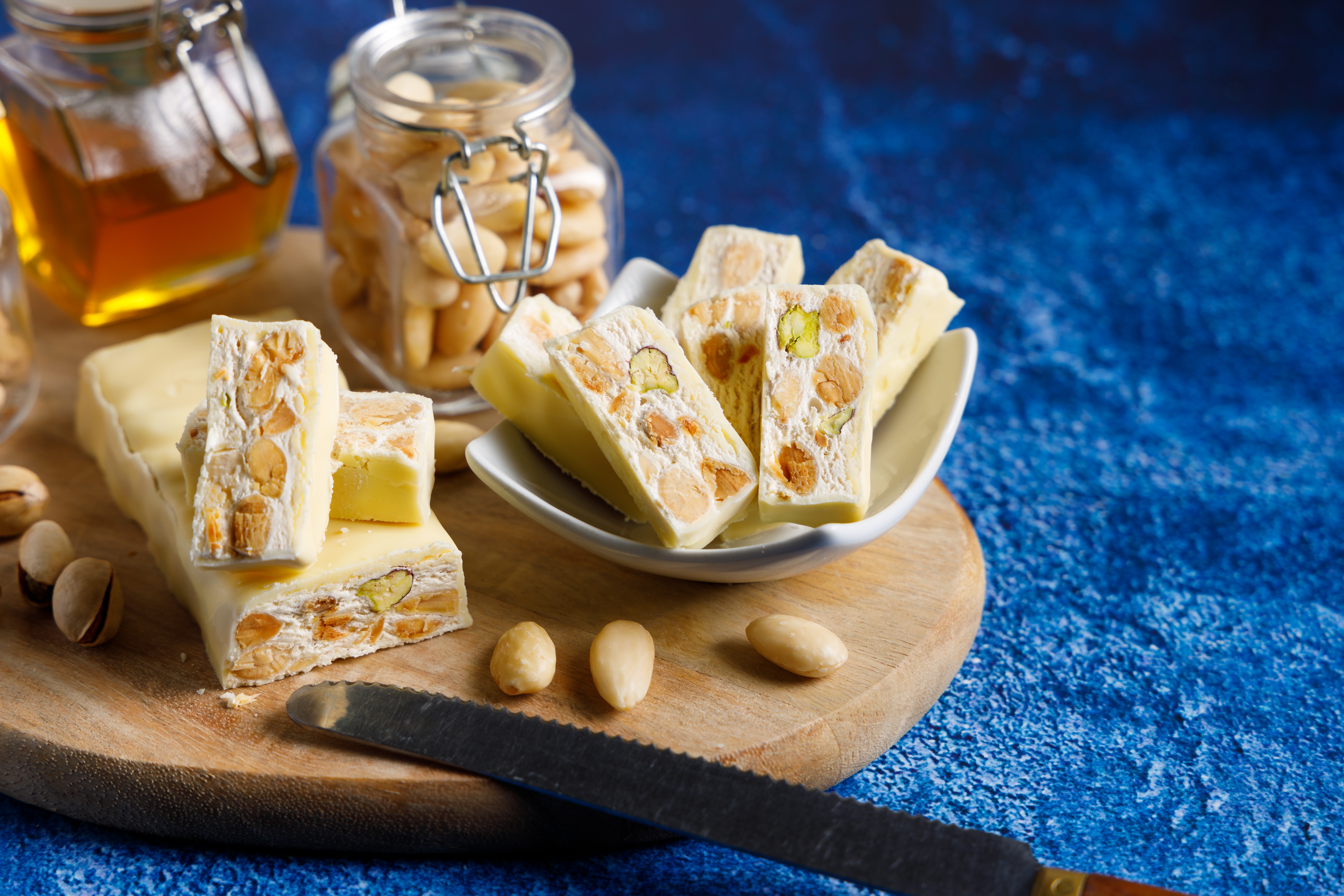 Autentisk italiensk torrone nougart med pistacienødder og mandler i hvid chokolade, ledsaget af frisk honning og hele nødder