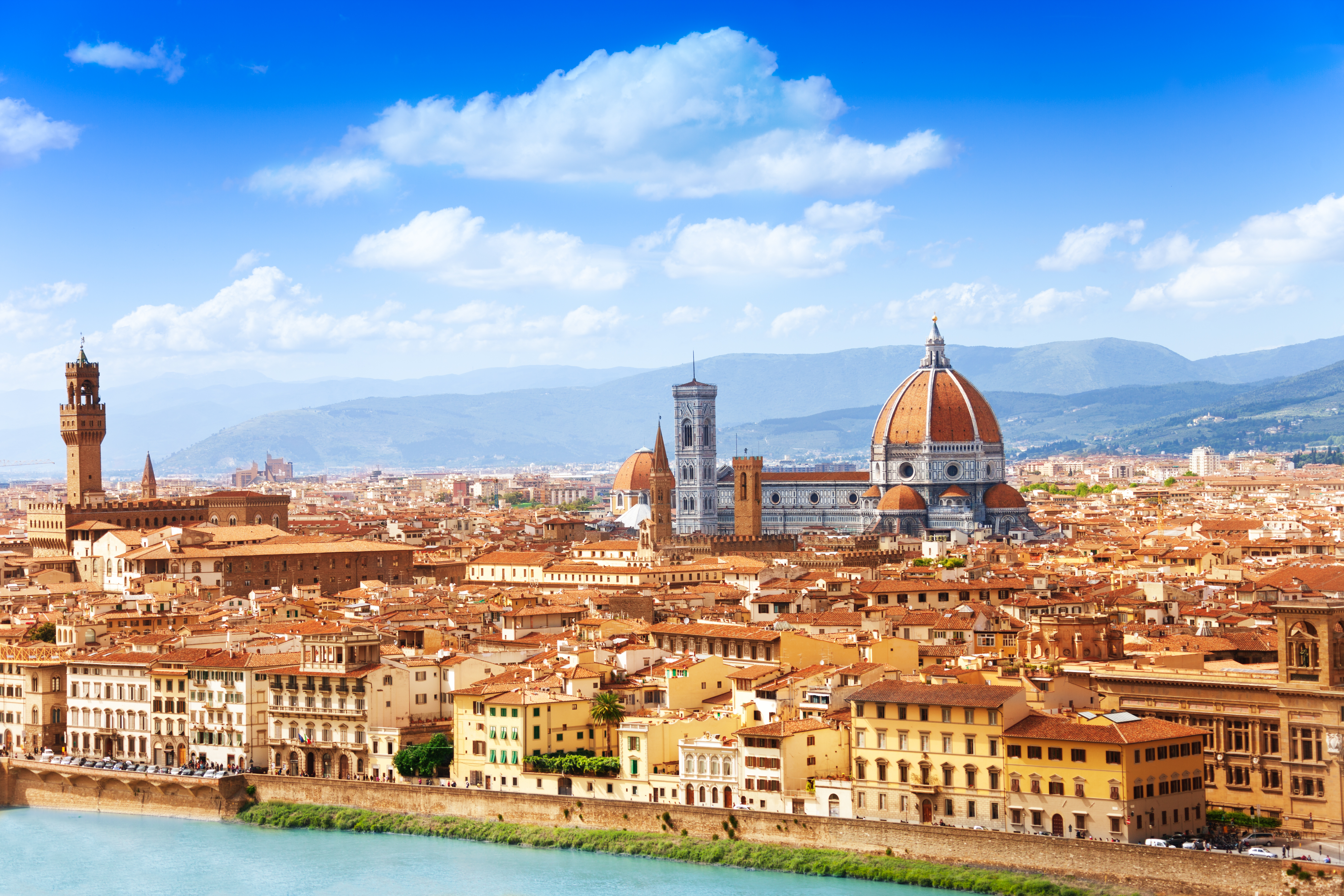 Storslået udsigt over Firenzes historiske centrum med den ikoniske Duomo-katedral og tårne under blå himmel i Toscana