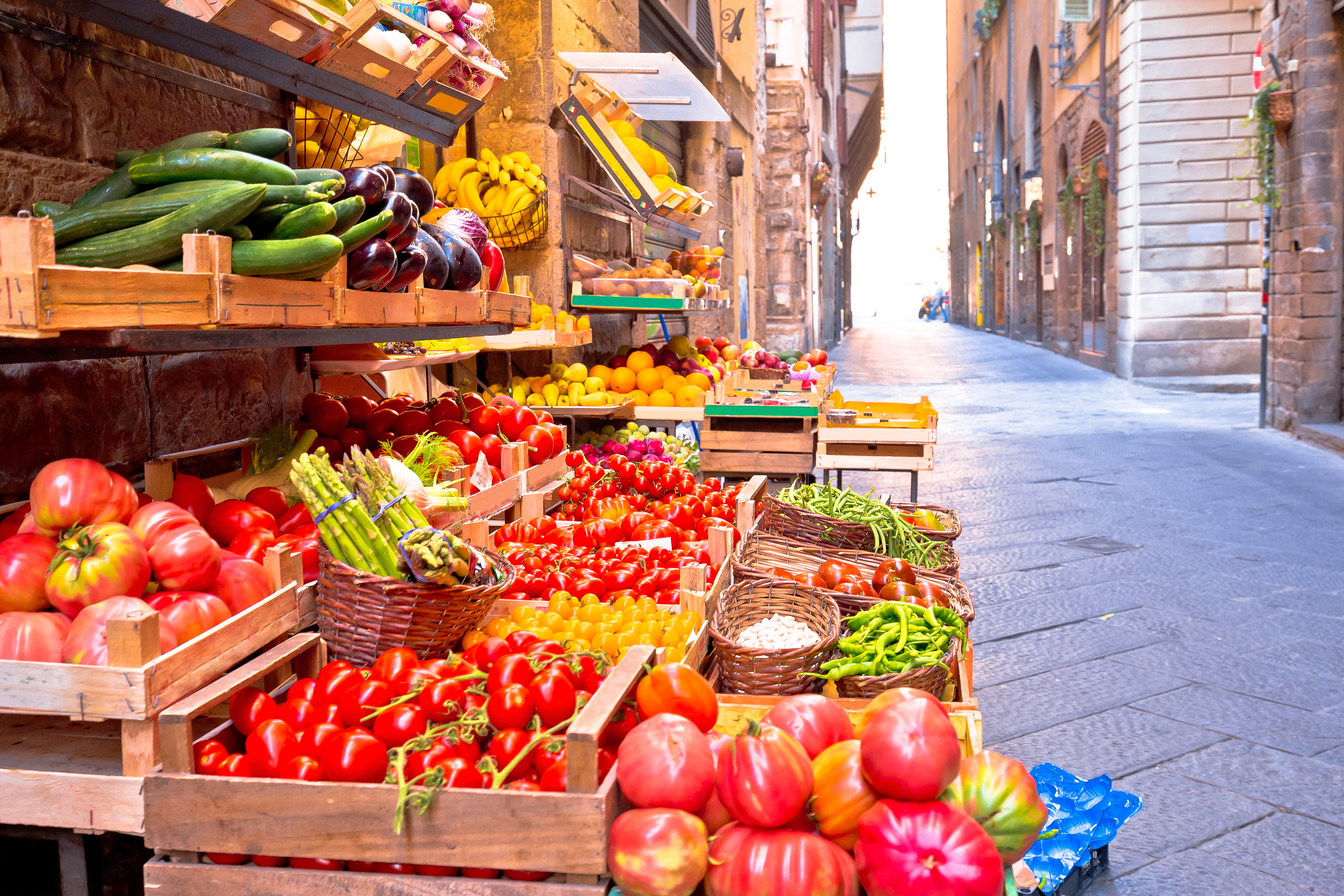 Traditionelt italiensk marked med et farverigt udvalg af friske frugter og grøntsager i en smal, historisk gade i Firenze, der indfanger den ægte toscanske stemning