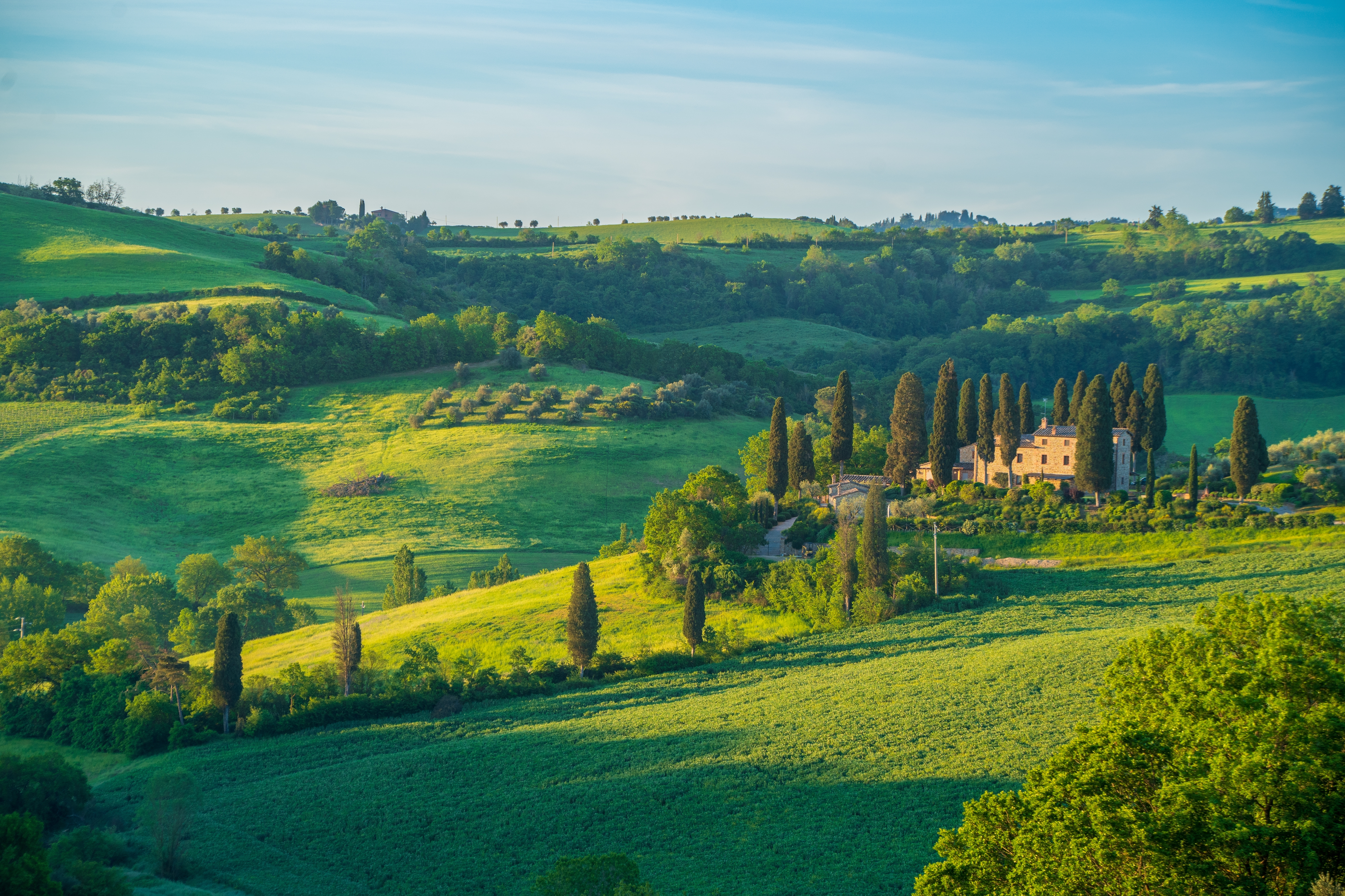 Pittoresk toskansk landområde med frodige grønne bakker, elegante cyprestræer og autentisk landejendom i Val d'Orcia