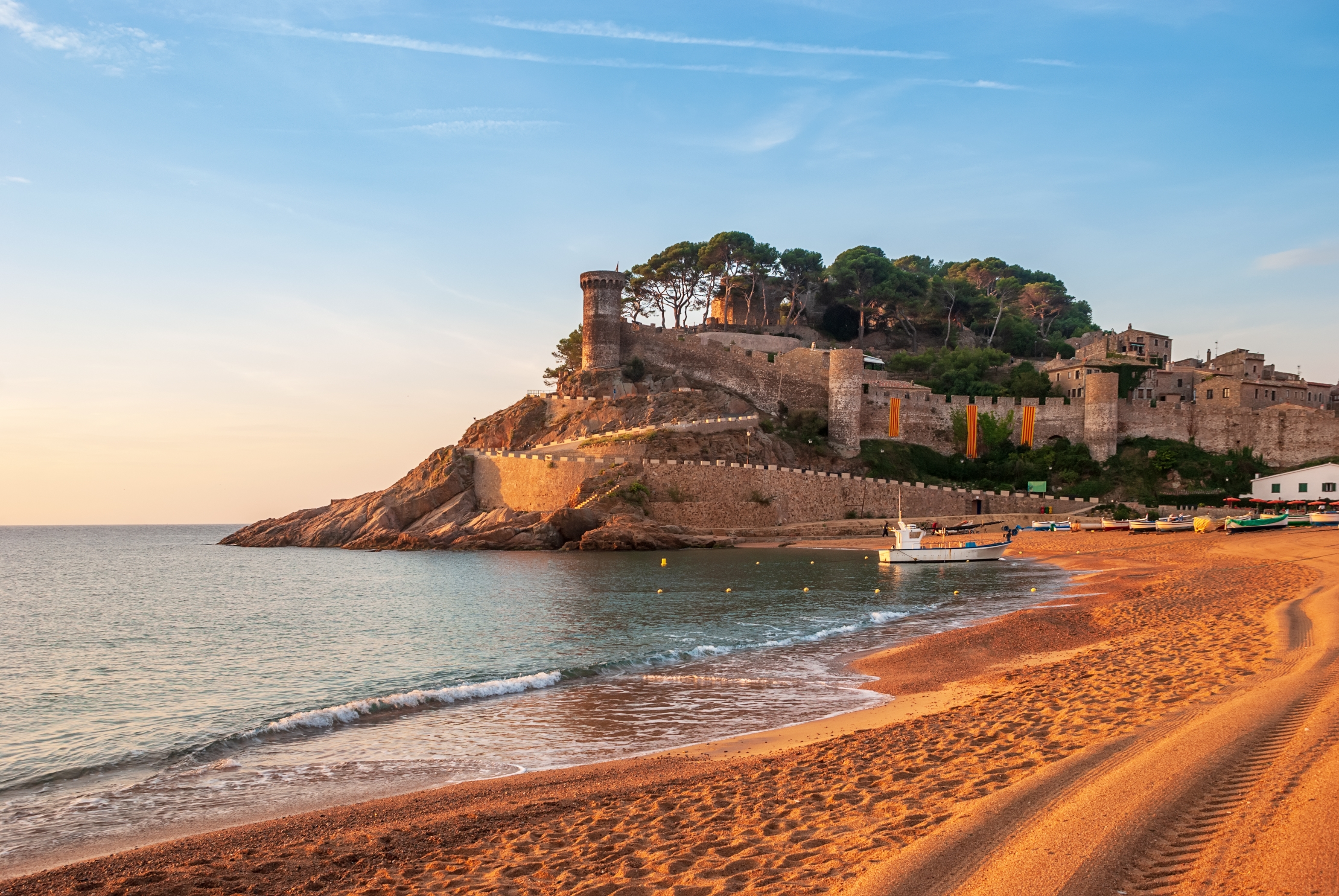 Idyllisk udsigt over Tossa de Mars middelalderlige fæstningsmure og tårn ved Costa Brava med rolig blå Middelhavsstrand