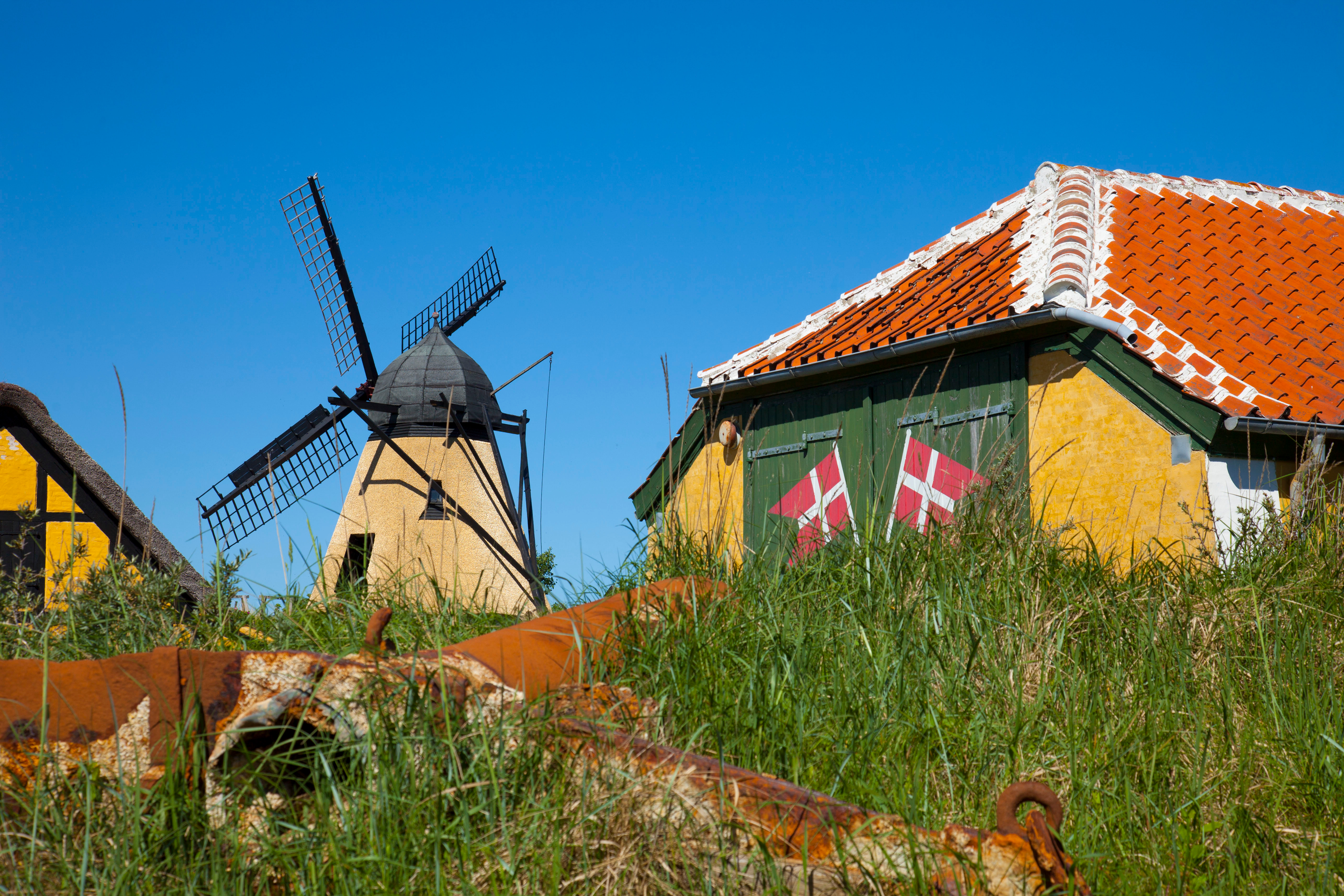 Charmerende dansk vindmølle ved historiske bygninger med røde tegltage og grønne områder