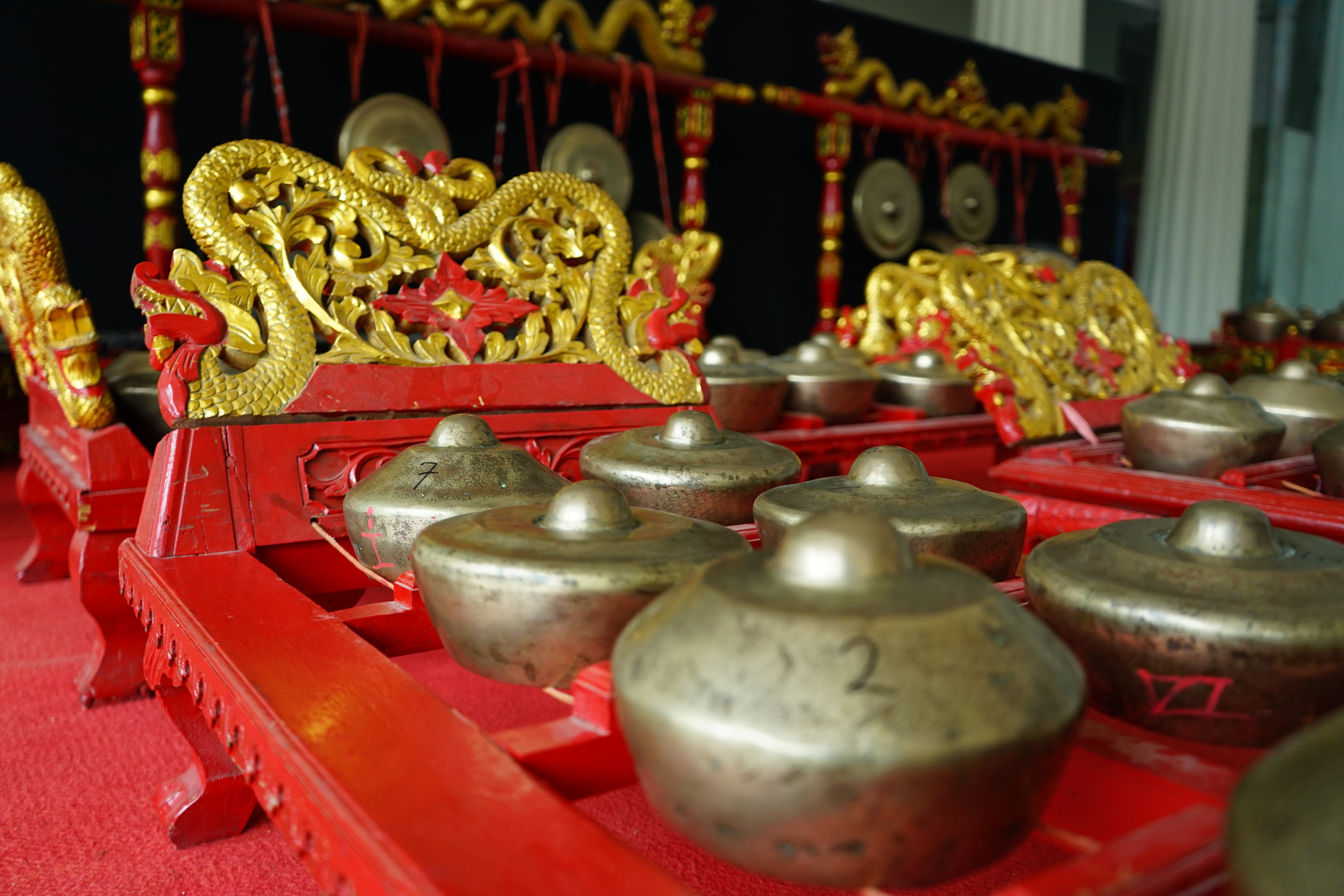 Traditionelt gamelan-orkester med gyldne drage-udskæringer og bronzegonger på Java, Indonesien
