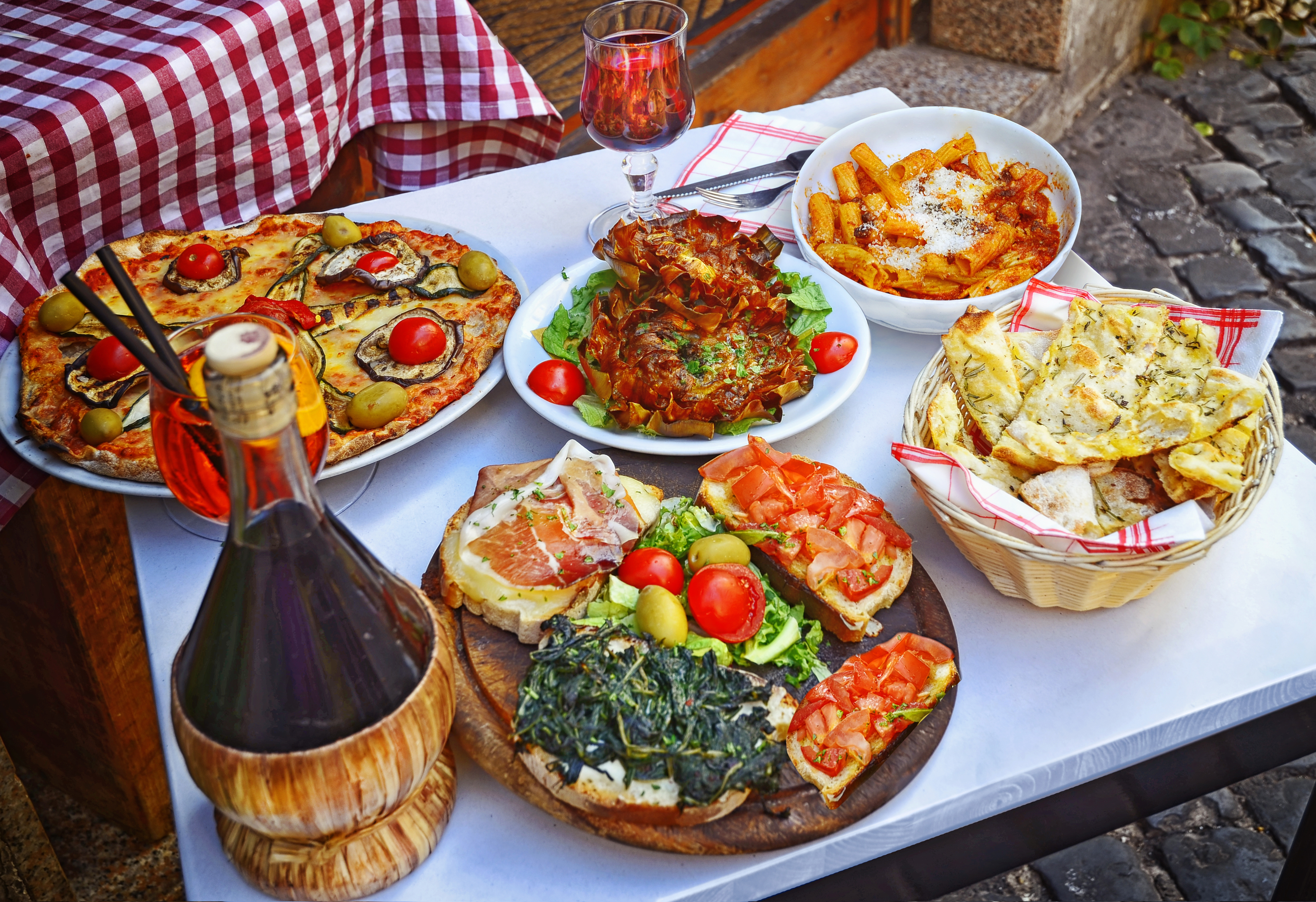 Traditionel italiensk middag med pizza og pasta på terrasse under ferie