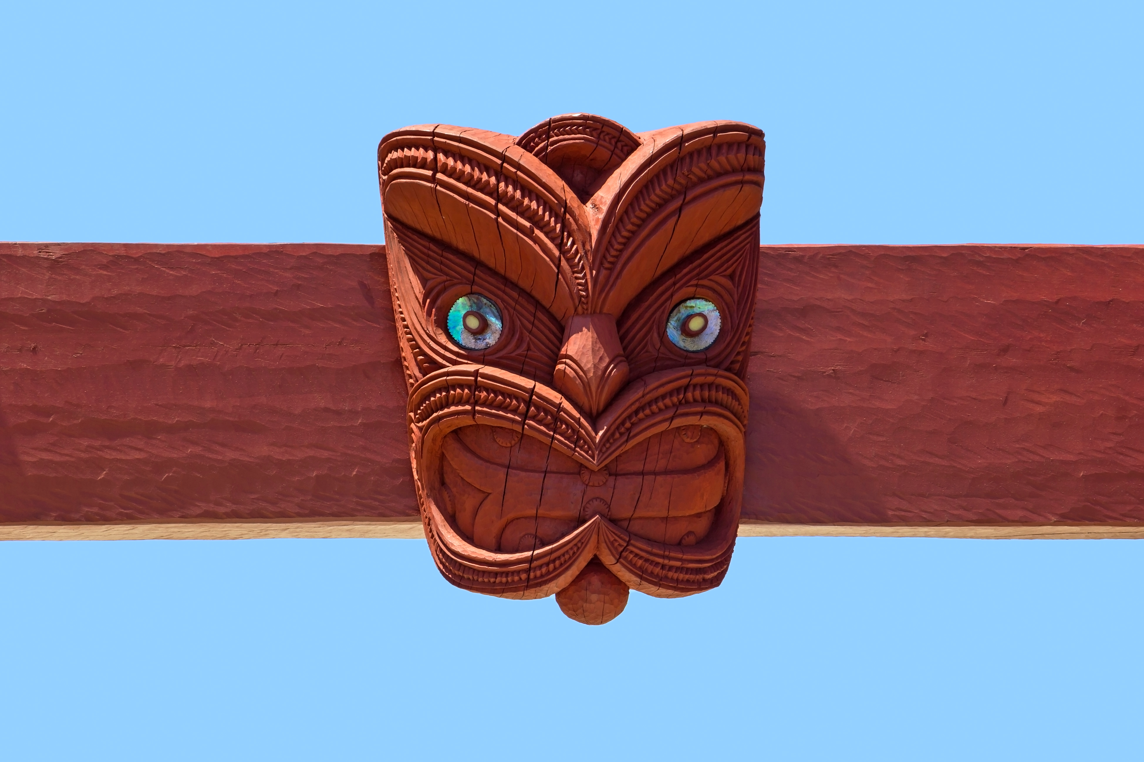 Klassisk maori tiki-udskæring med blå øjne og detaljerede mønstre i New Zealand