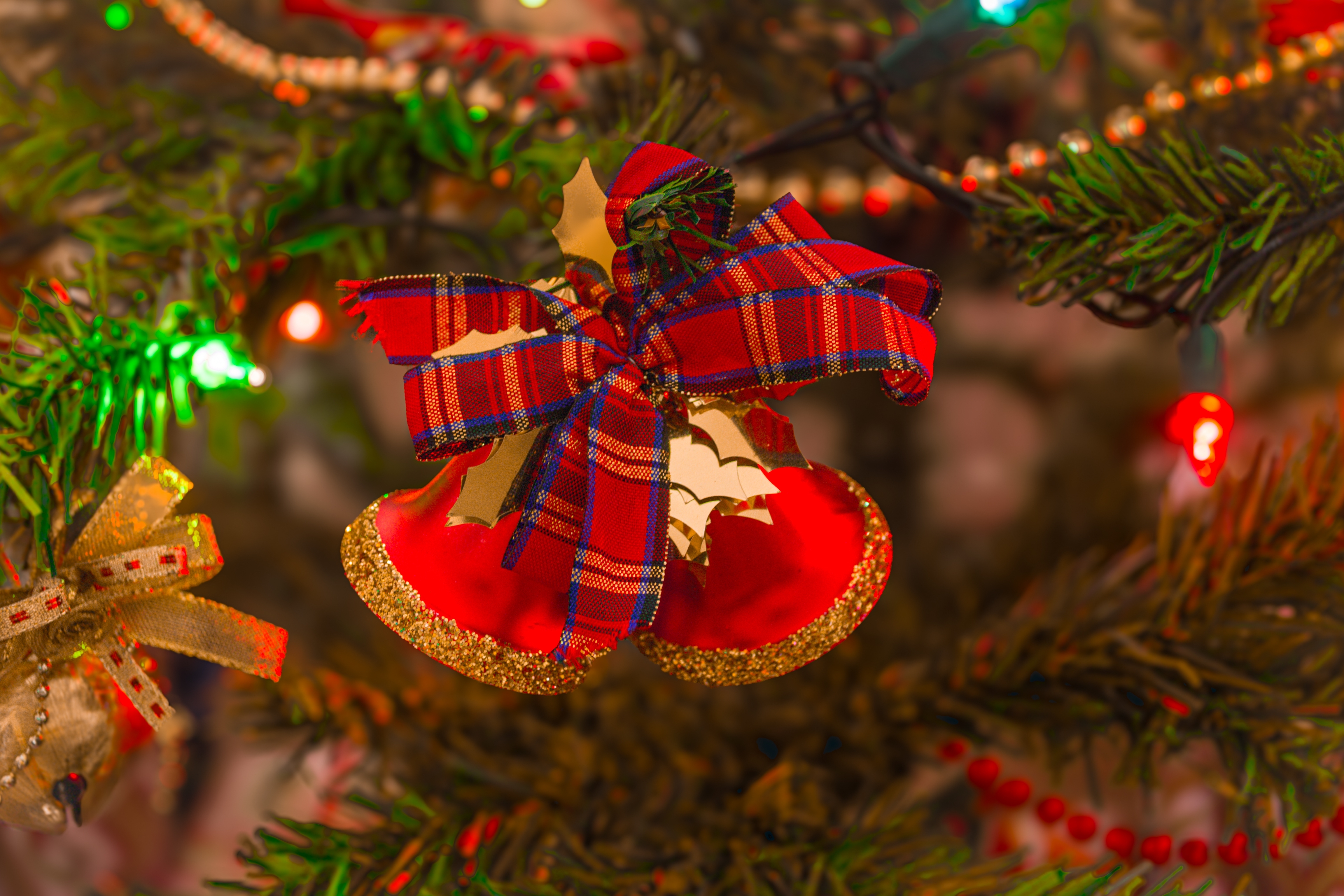 Håndlavet skotsk juledekoration med røde klokker og tartan bånd på juletræ med glitrende lys
