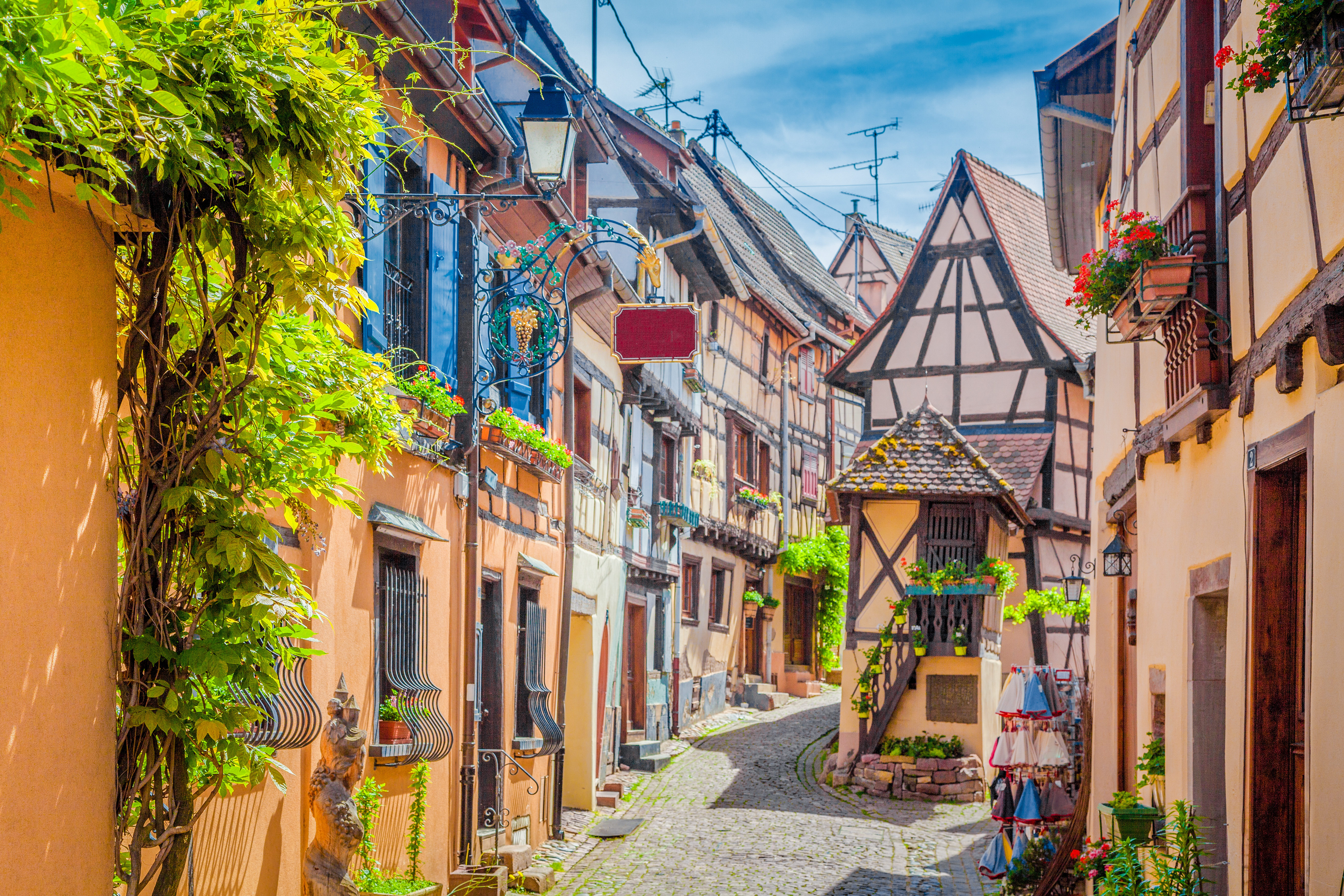 Idyllisk smal gade med farverige traditionelle huse og blomster i Colmar Alsace